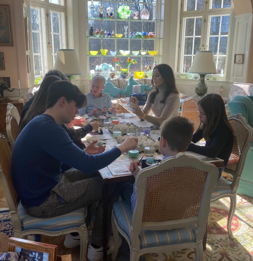 Familjen samlad i den soliga matsalen där drottning Margrethe har sin glassamling på hyllorna i burspråksfönstret. Danska kungafamiljen Målar ägg Påsk Kronprinsessan Mary Drottning Margrethe