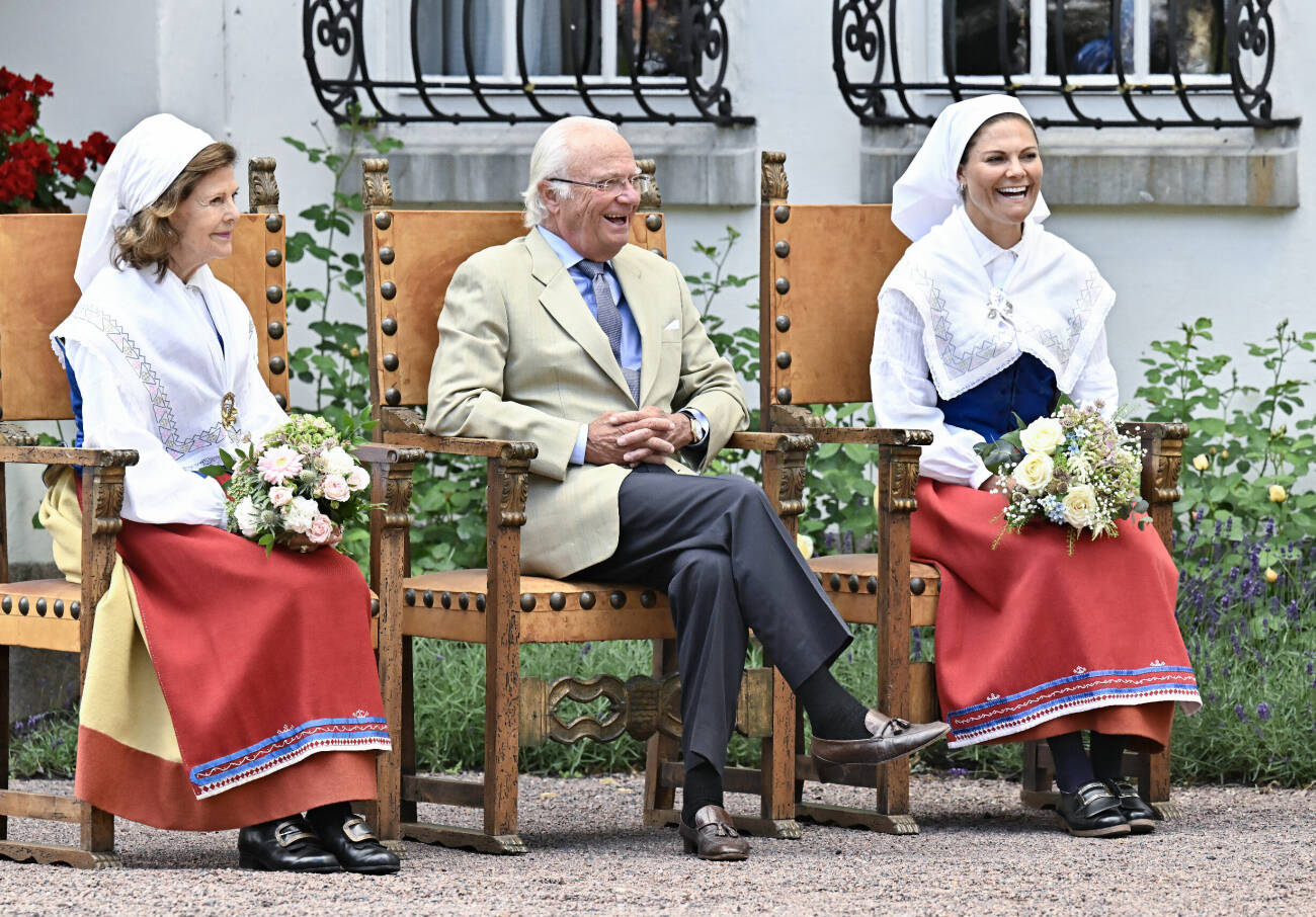Drottning Silvia, Kung Carl XVI Gustaf och Kronprinsessan Victoria sitter i på varsin stol i trä utanför Sollidens slott