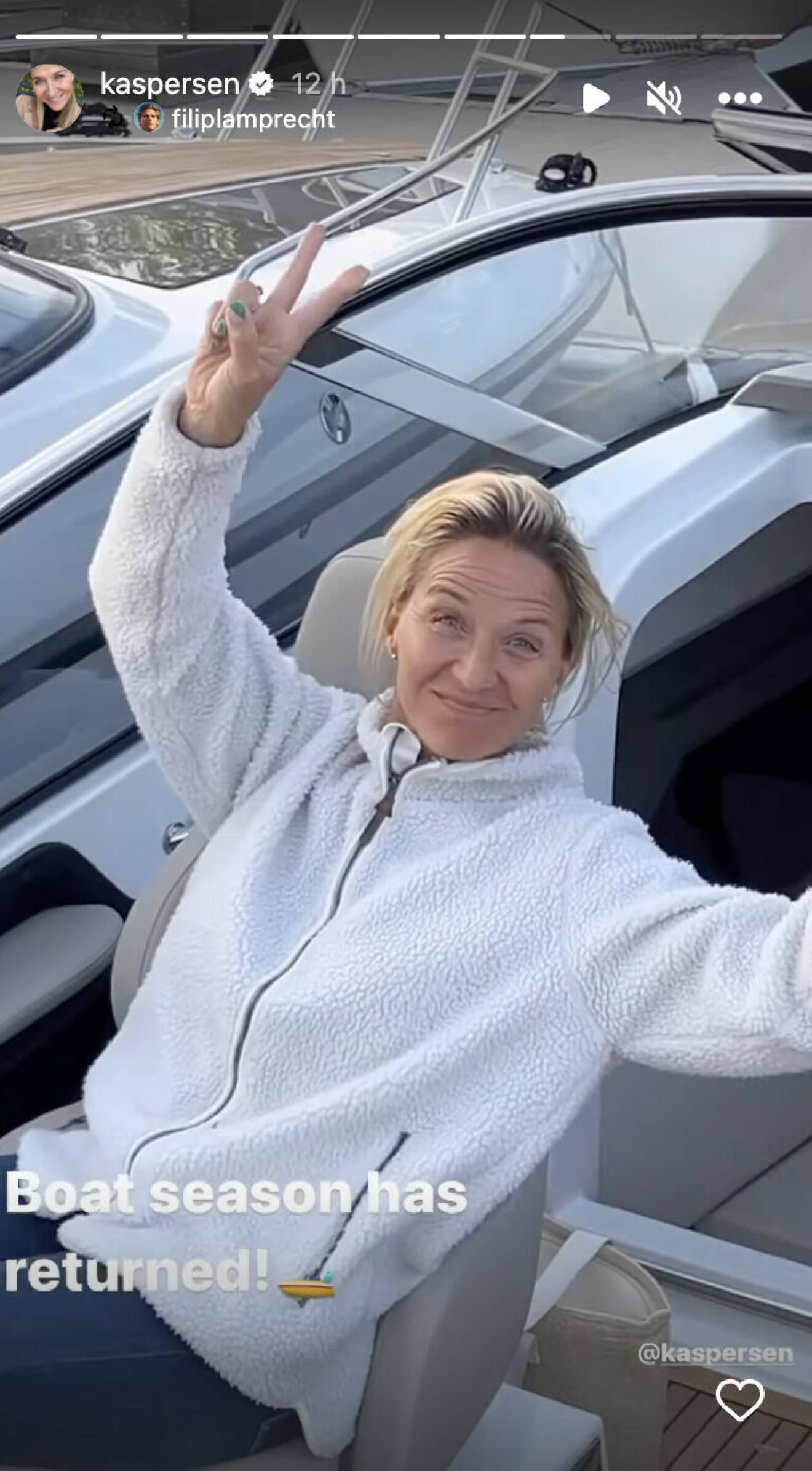 Kristin Kaspersen sitter på sin båt och håller sina fingrar i fredstecken