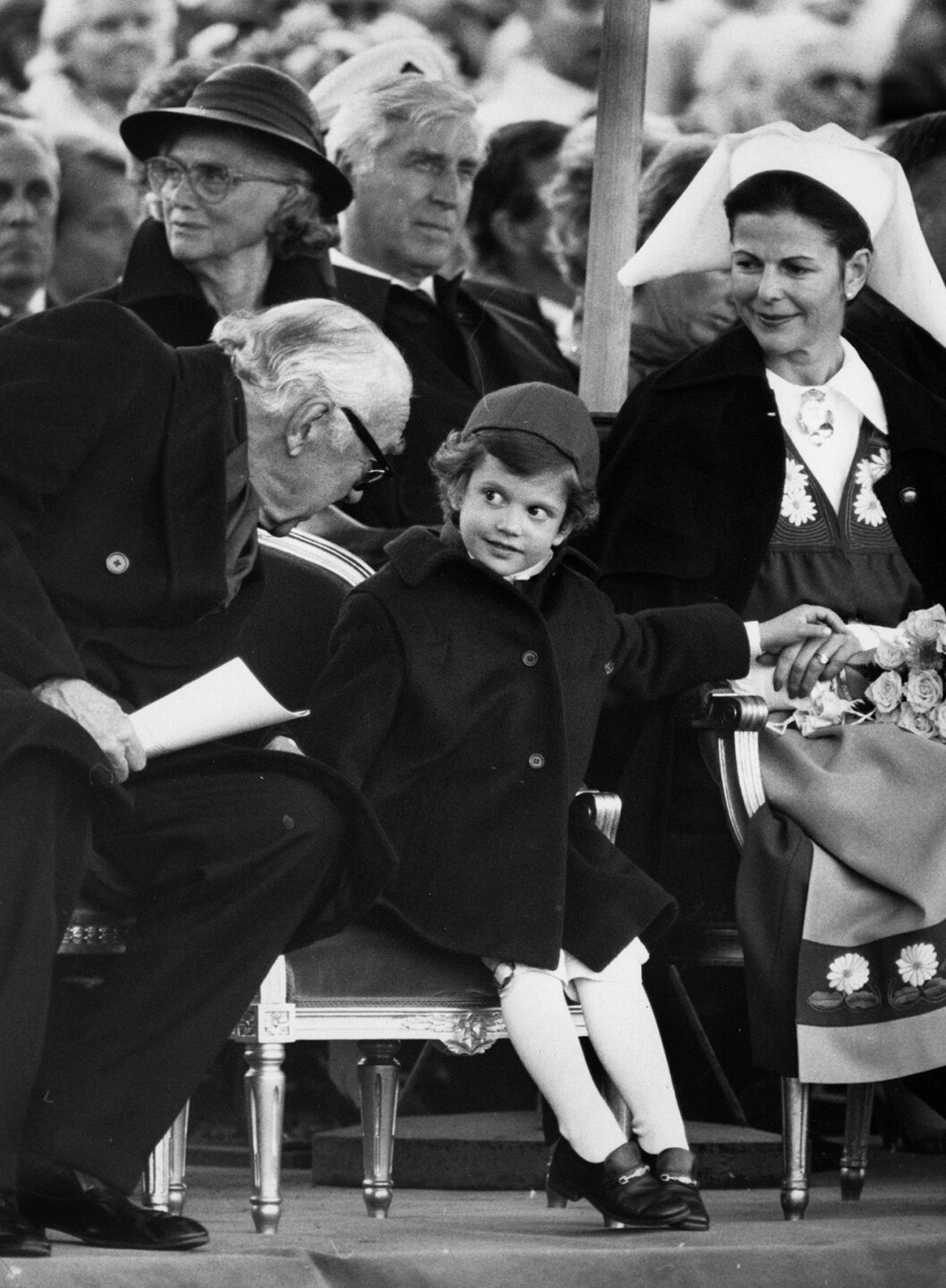 Prins Bertil viskar något till Carl Philip under firandet av Sveriges nationaldag 1983. Prins Bertil och prins Carl Philip