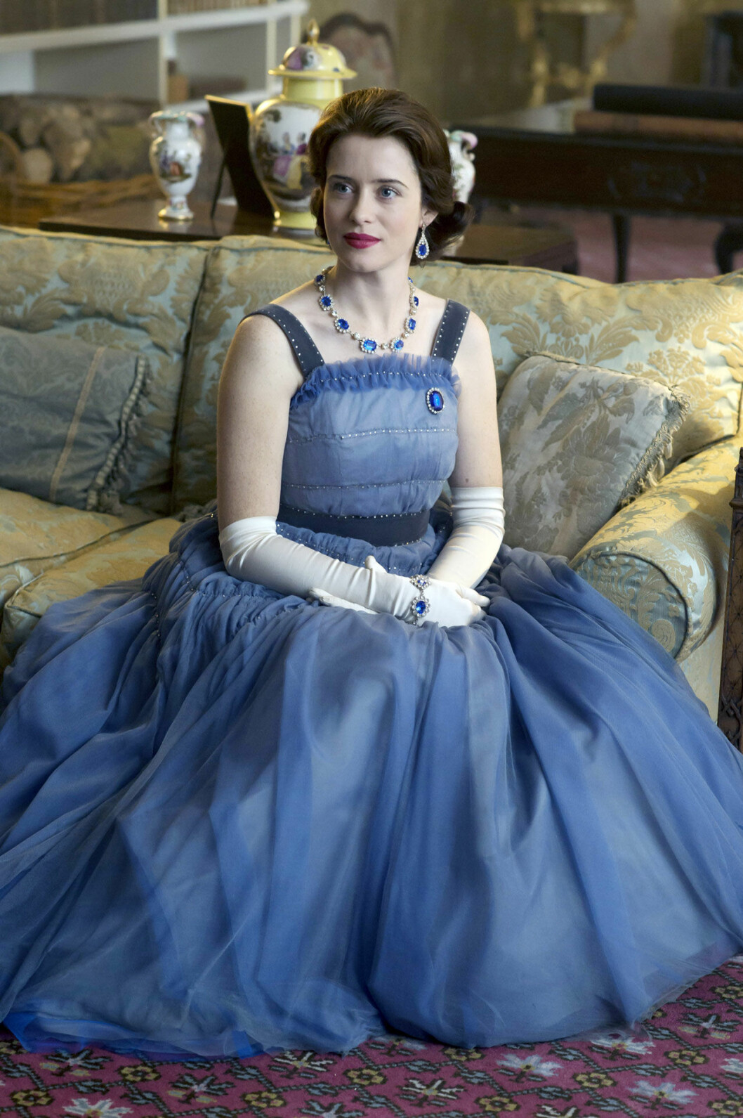 Här förstärker soffans tyg klänningens skira kvalitet, medan den blå färgen symboliserar drottningens ungdom.