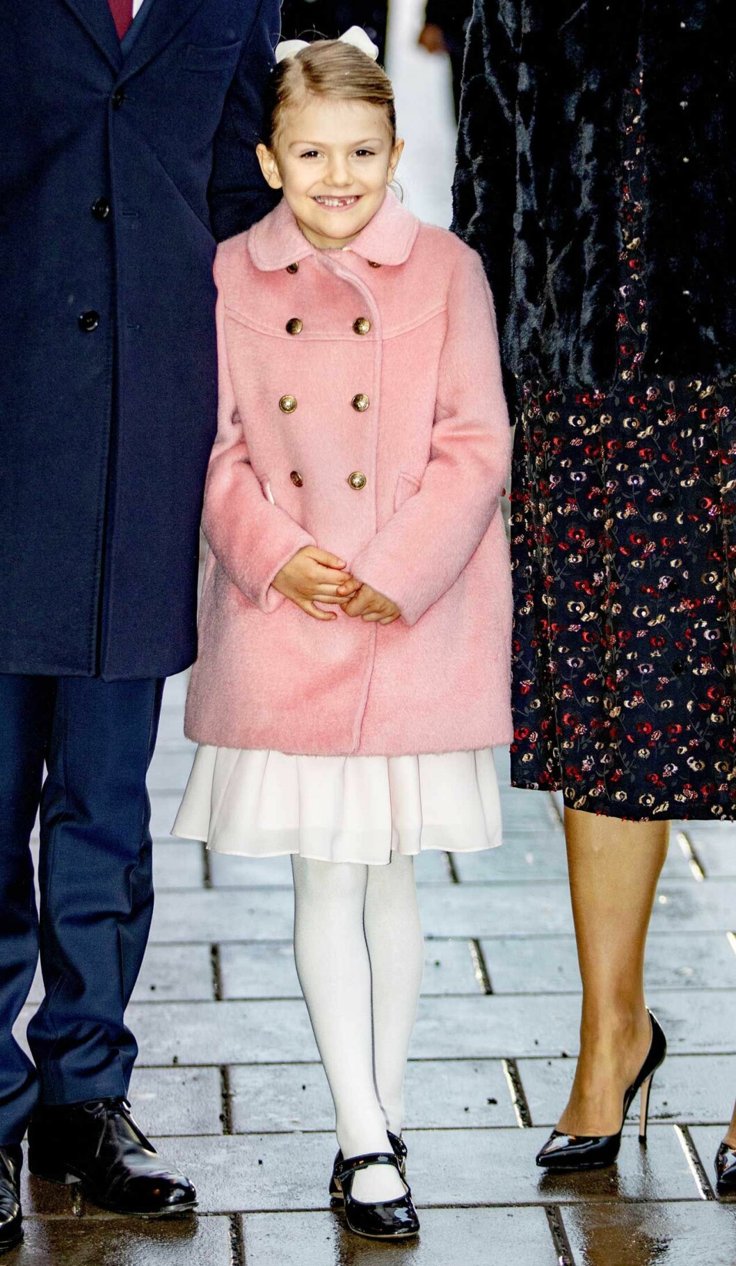 Estelle visar tandgluggen. Lilla pyssliga prinsessan Estelle i rosa kappa. Visar tandgluggen.