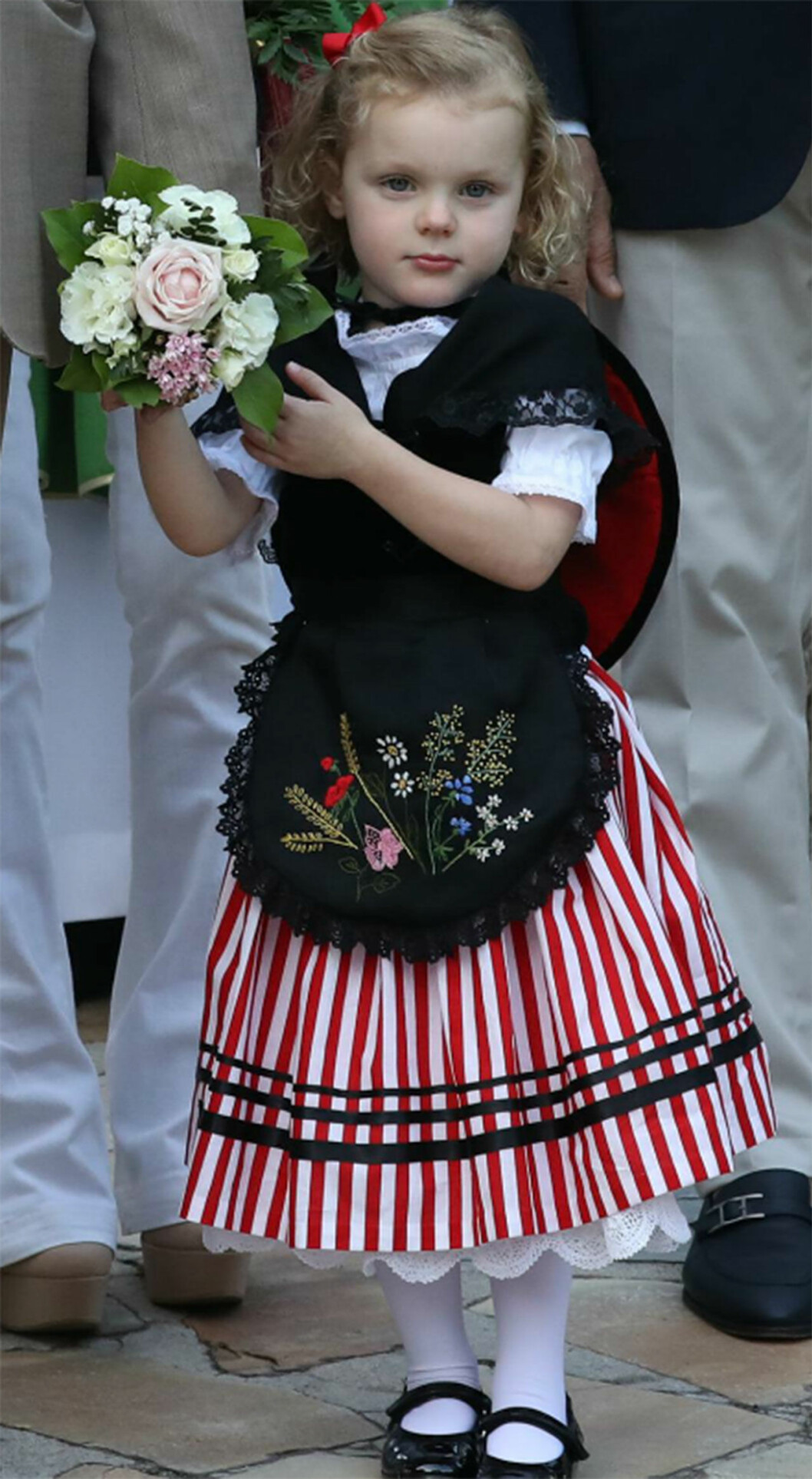 Prinsessan Gabriella bar en rödrandig kjol och röd rosett i håret