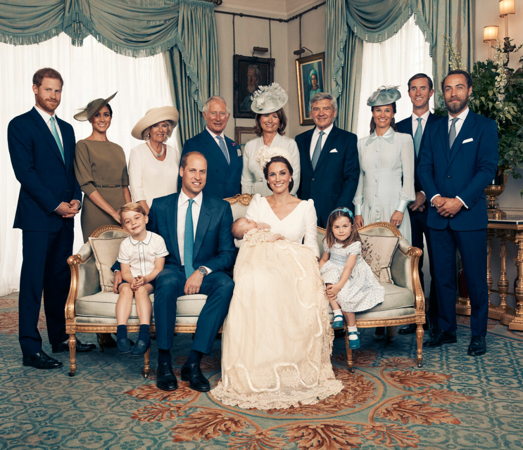 Här sitter alla rakt. Och här var det Harrys och Meghans tur att stå längst ut på kanten. Familjebilden från prins Louies dop.