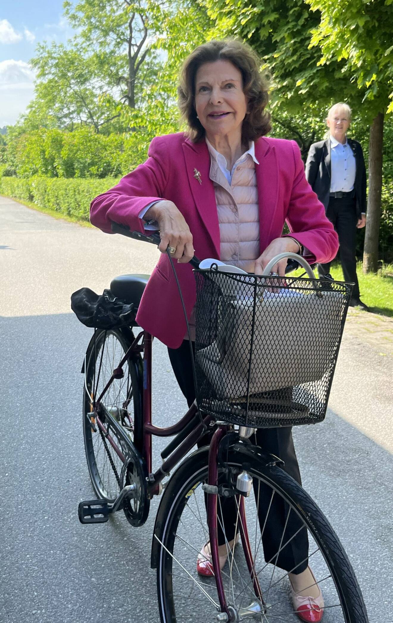Drottning Silvia på cykel utanför Silviahemmet