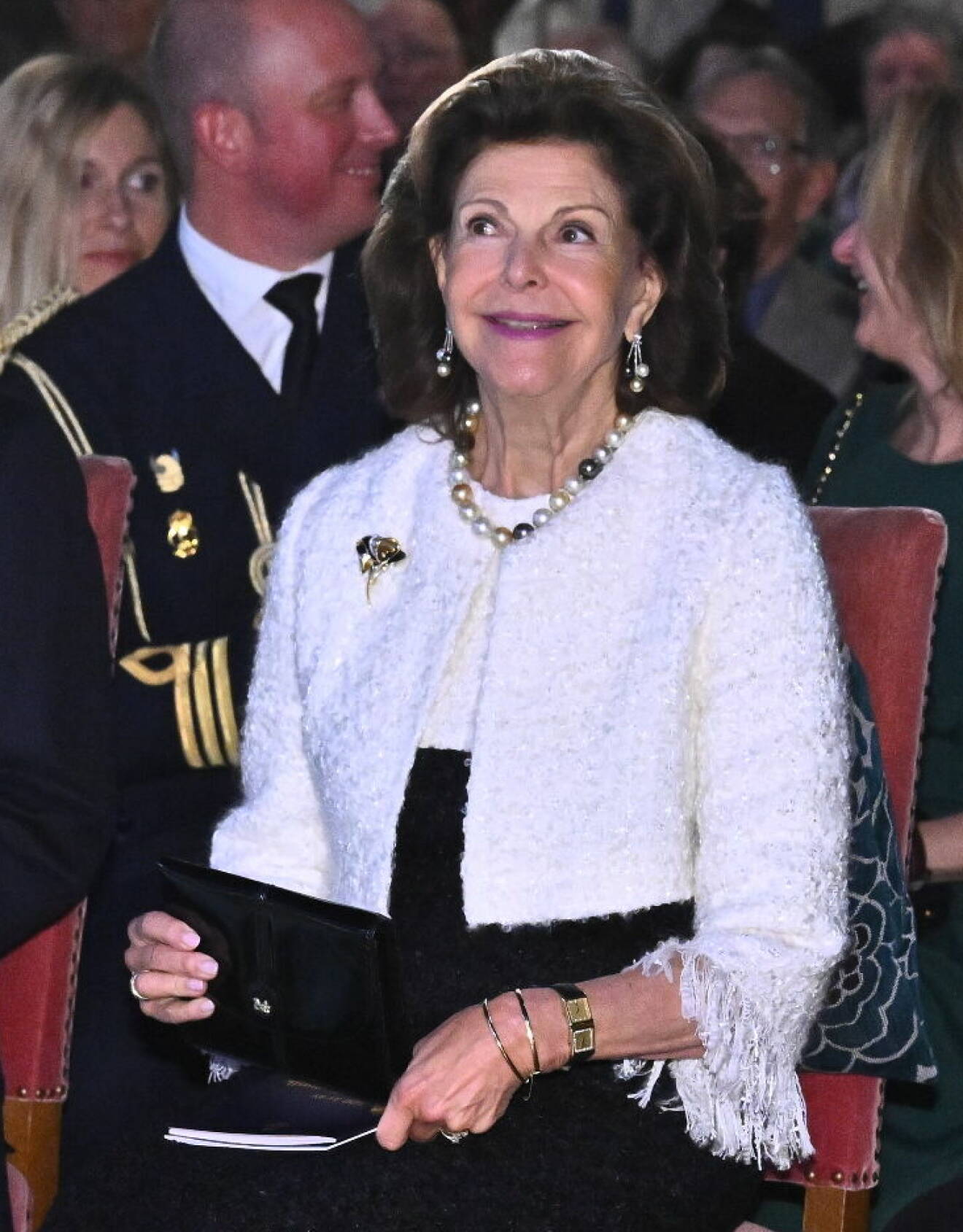 Drottning Silvia festklädd i vit dräktjacka med fransar