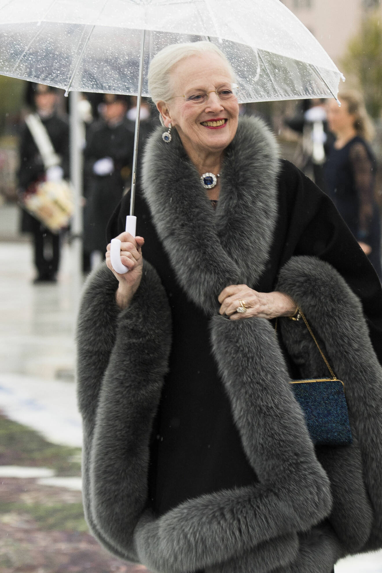 Drottning Margrethe ler med ett paraply i handen