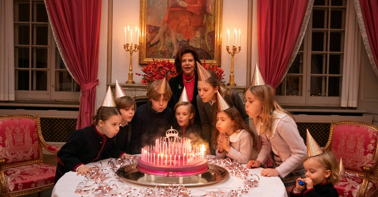 Drottning Silvia blåser ut tårtljus med prins Alexander, prins Oscar, prins Nicolas, prinsessan Adrienne, prinsessan Estelle, prins Julian och prinsessan Leonore