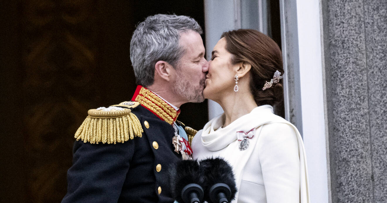 Kung Frederik och drottning Mary kysser varandra på slottsbalkongen