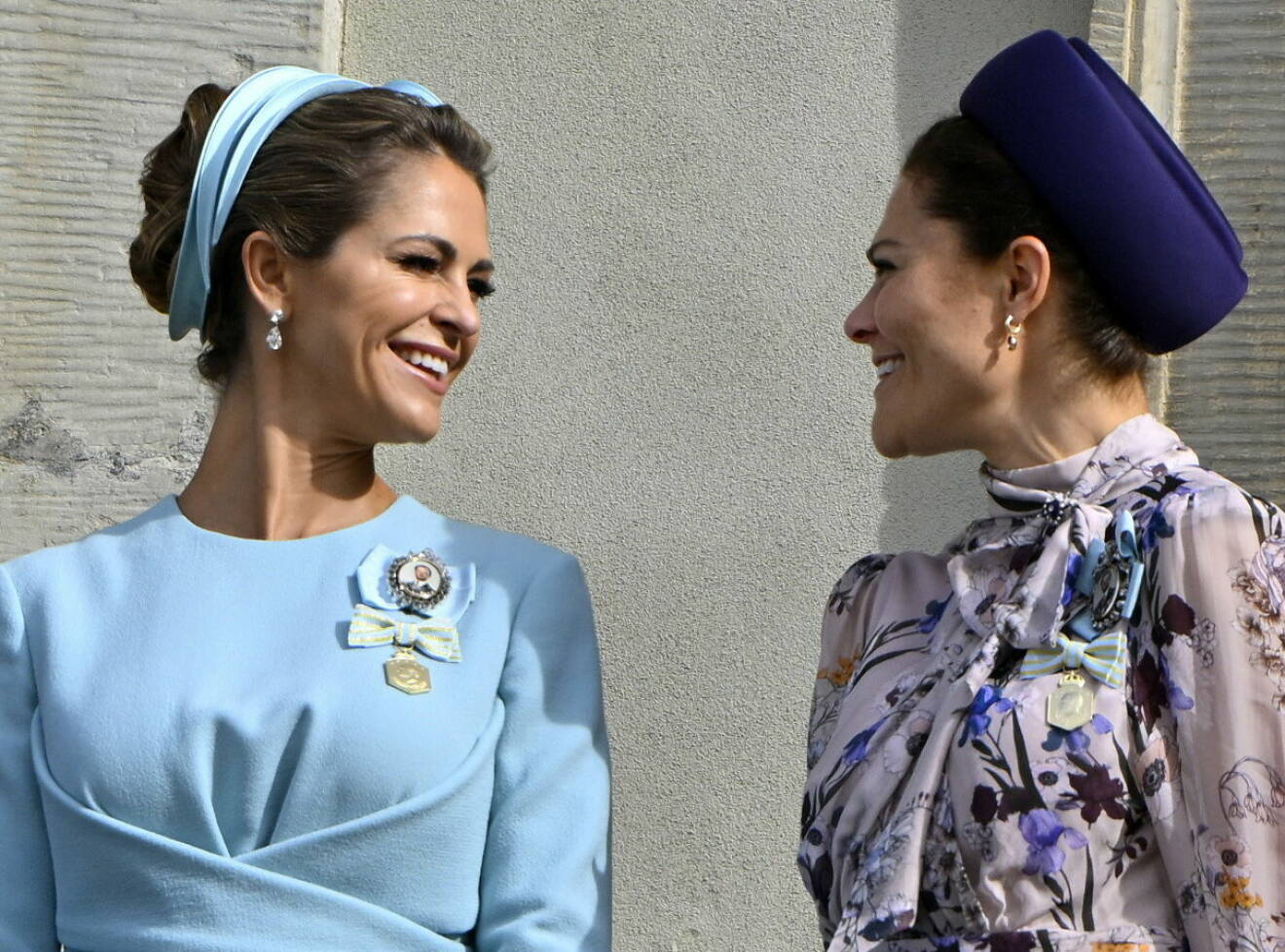 Prinsessan Madeleine och kronprinsessan Victoria tittar på varandra och skrattar