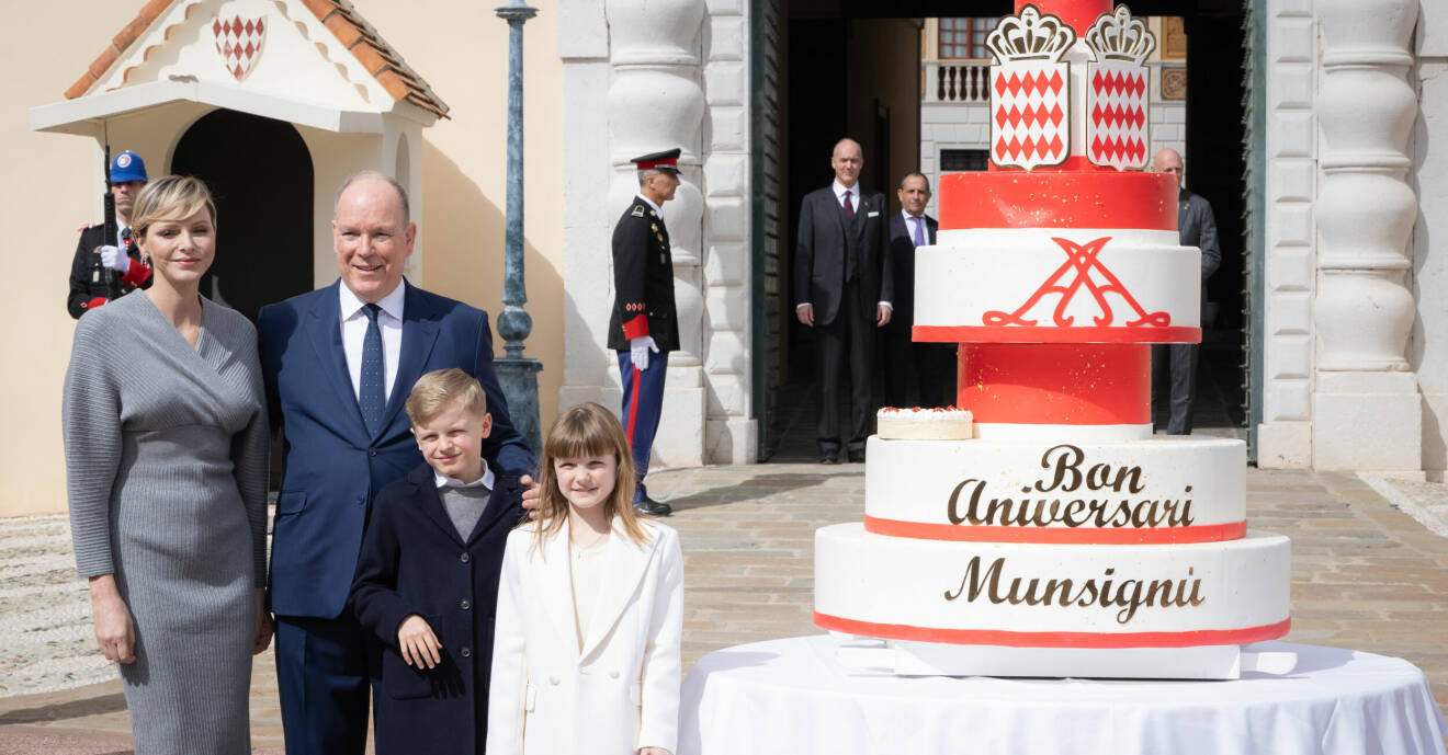 Furstinnan Charlene, furst Albert, prins Jacques och prinsessan Gabriella poserar bredvid en stor tårta
