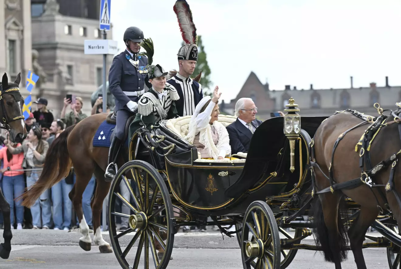 Drottning Silvia och kung Carl Gustaf åker i kortege med häst och vagn genom Stockholm