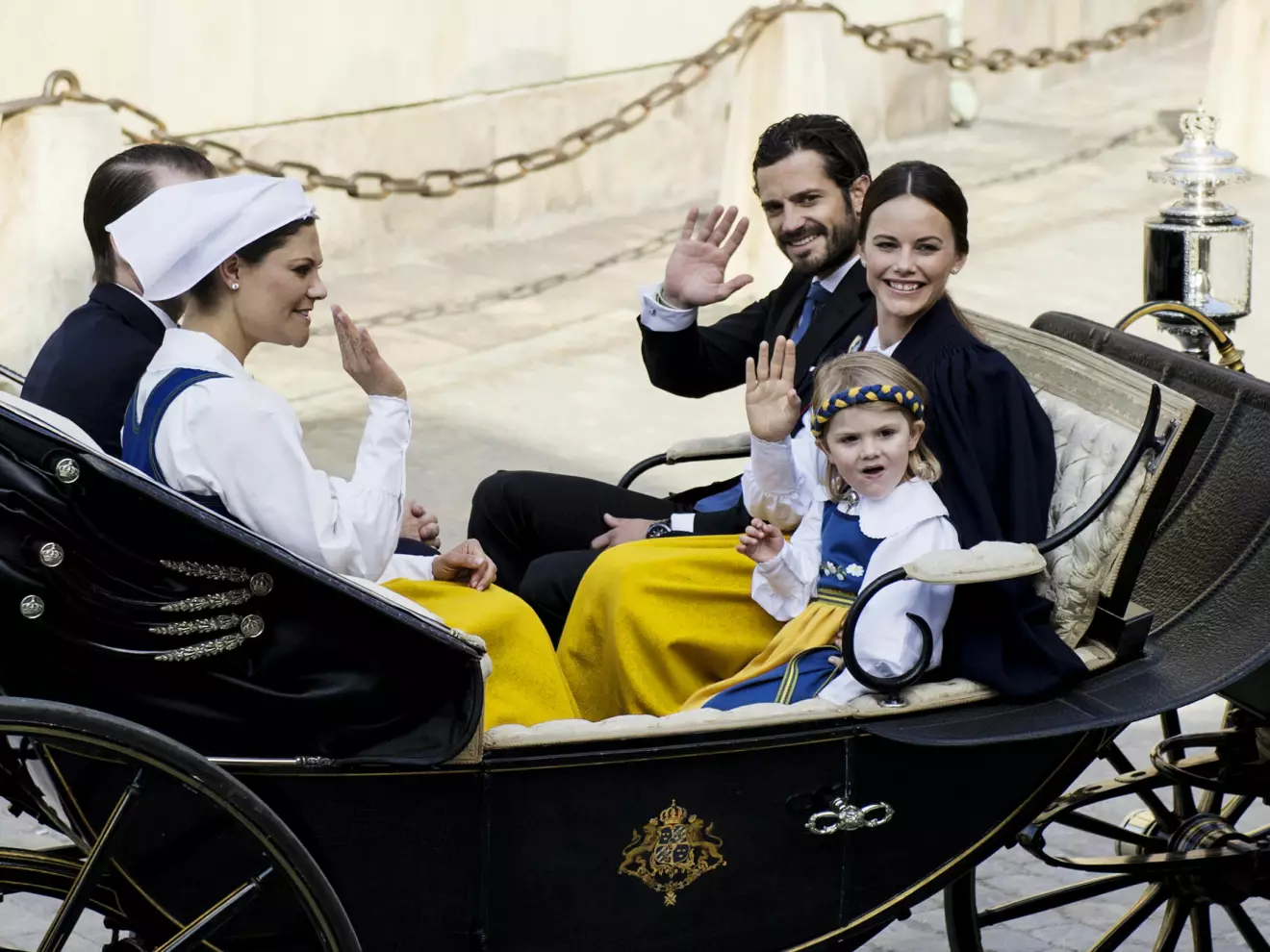 Prins Daniel, kronprinsessan Victoria, prins Carl Philip, prinsessan Sofia och prinsessan Estelle i öppen vagn i kortegen på väg från Stockholms slott till nationaldagsfirandet på Skansen 2015