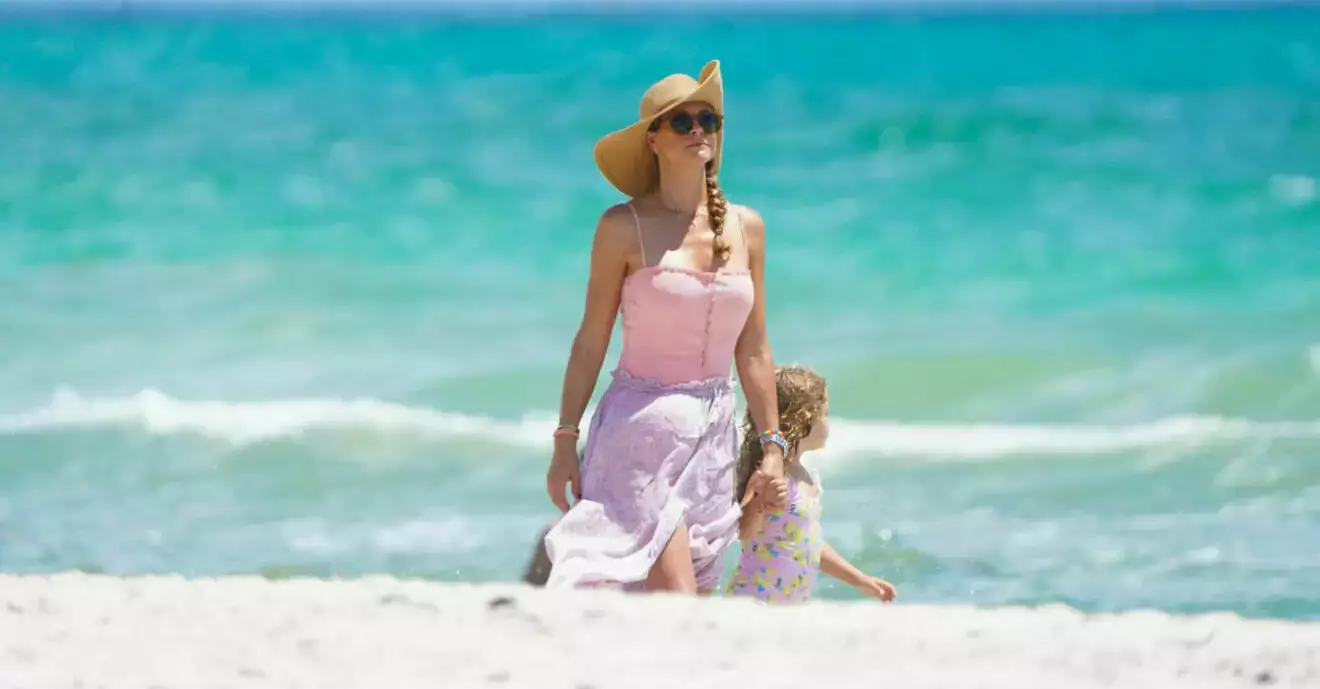 Prinsessan Madeleine håller prinsessan Adrienne i handen på stranden