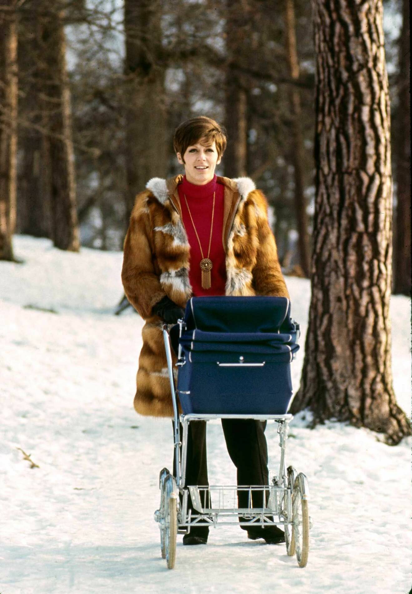 Lycklig mamma på vinterpromenad med barnvagnen 1970.