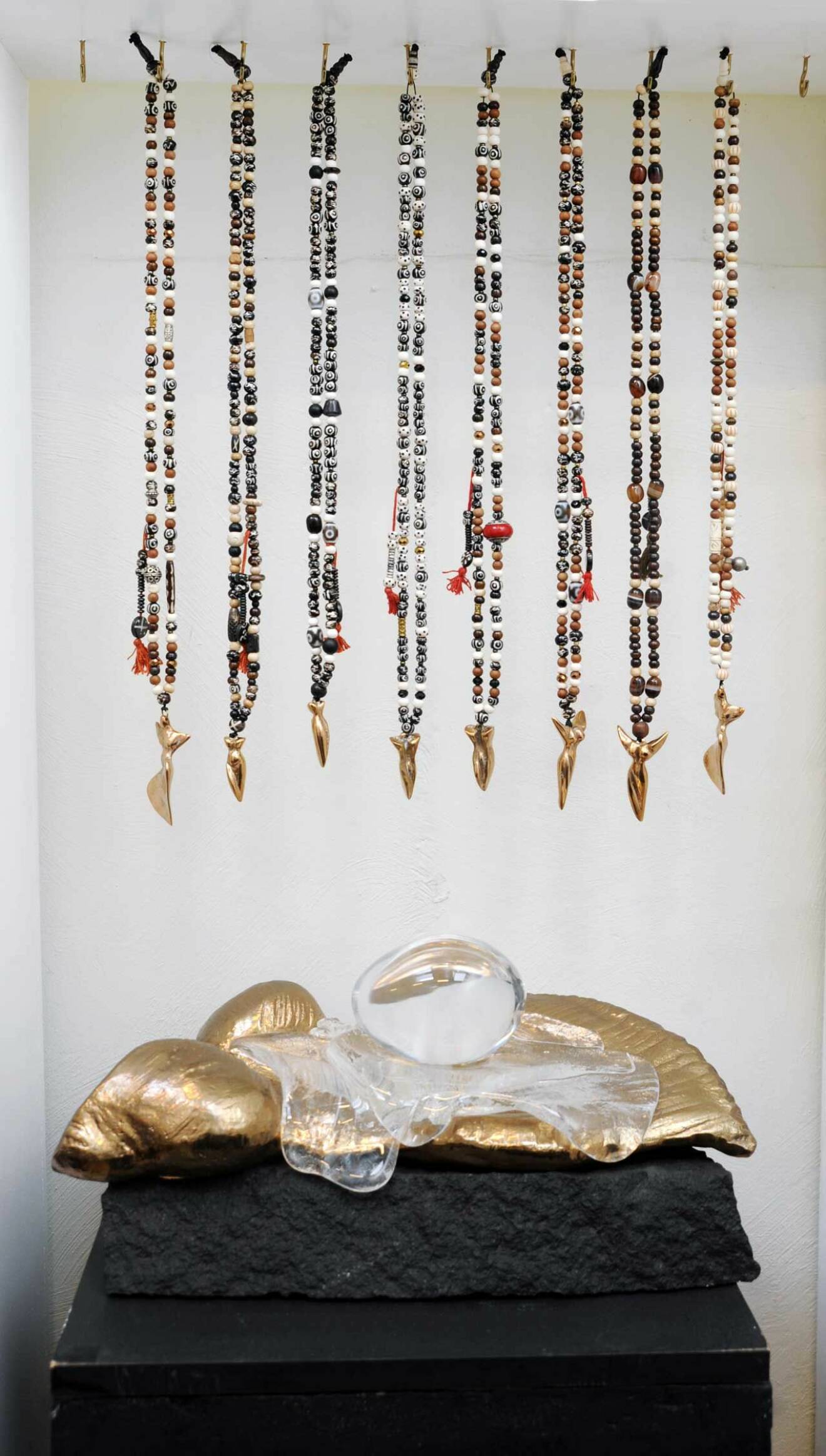 Halsband med tibetanska bönepärlor och bronshängen ovanför en skulptur i brons.