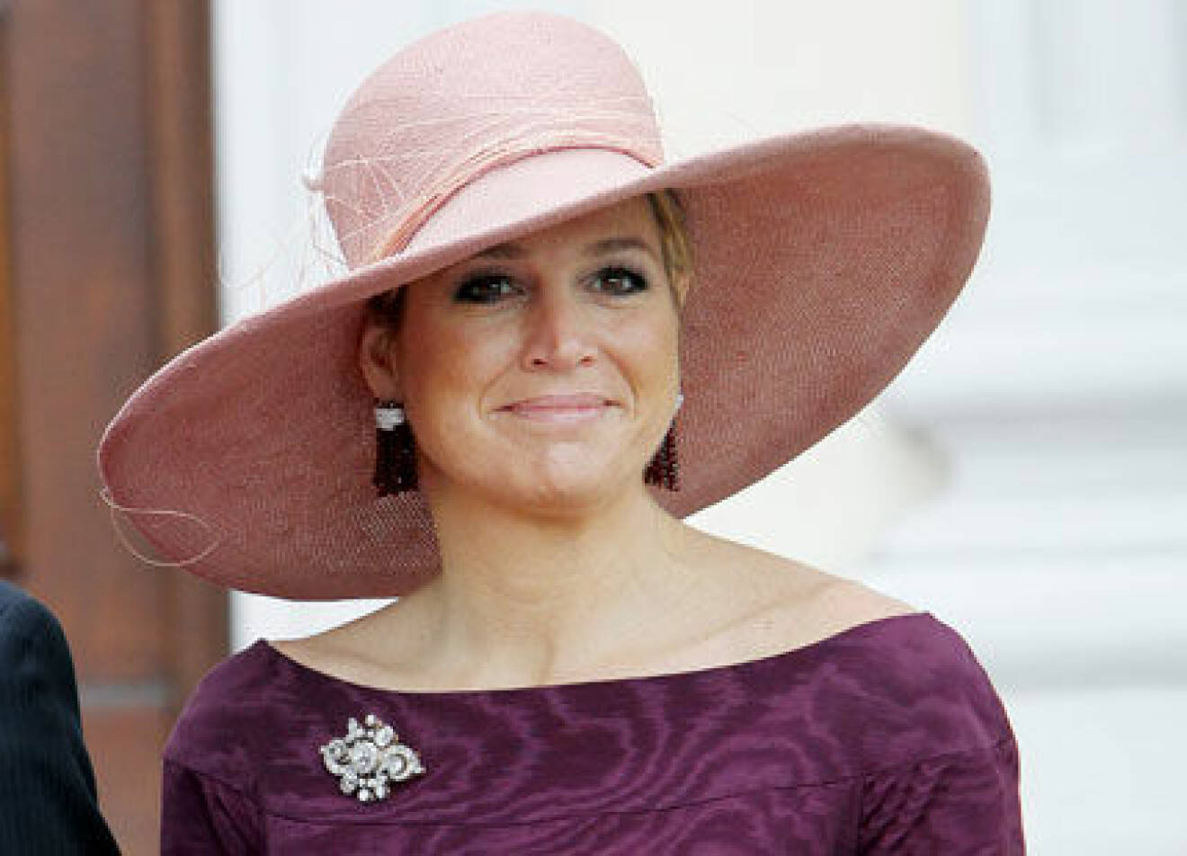 Drottning Maxima i rosafärgad hatt och lila klänning.