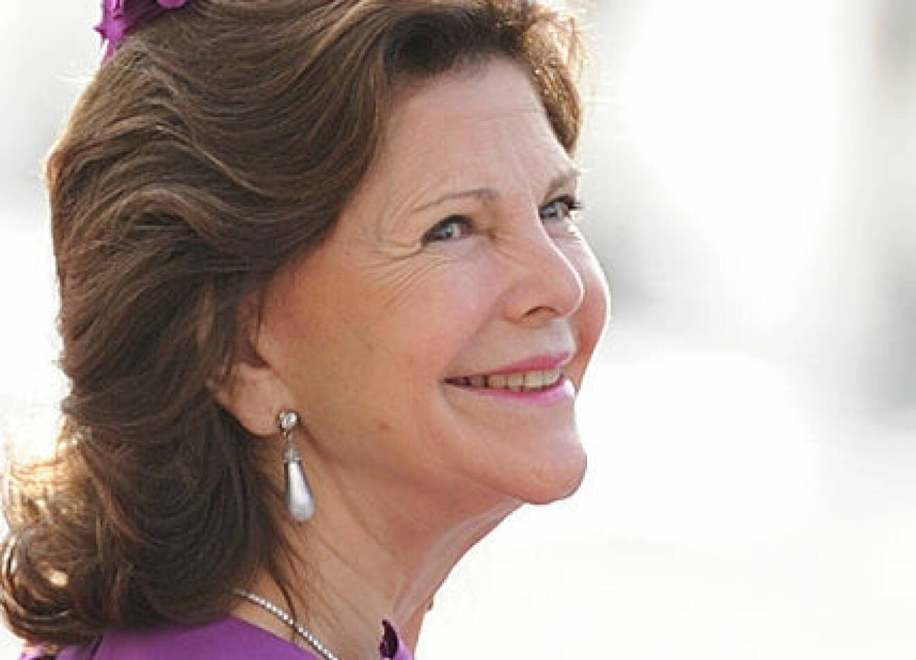 En leende drottning Silvia med stora silverfärgade droppformade örhängen