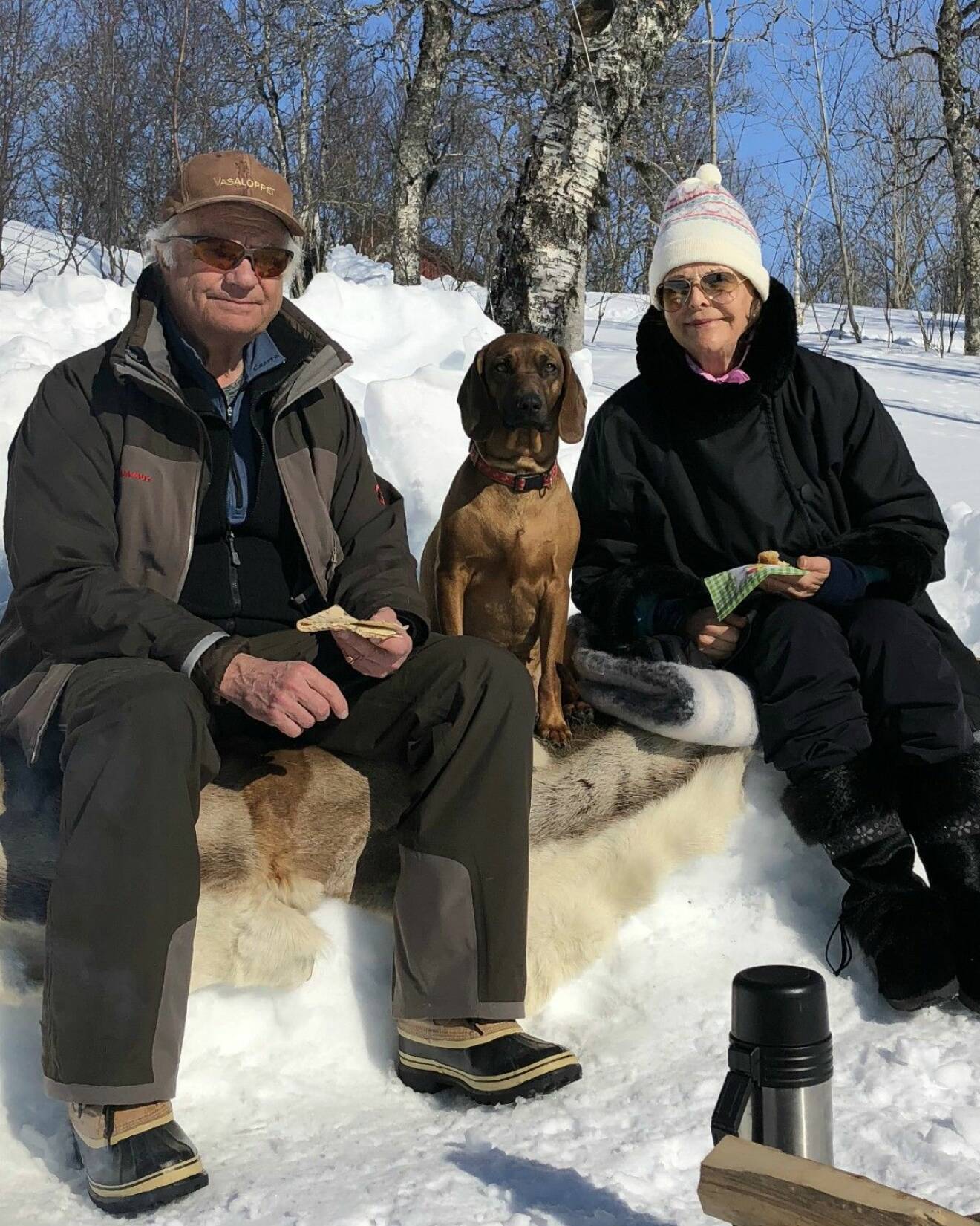 Kung Carl Gustaf och drottning Silvia och hunden Brandie firar påsk i Storlien våren 2018. På utflykt, de sitter på ett renskinn och har med sig termos.