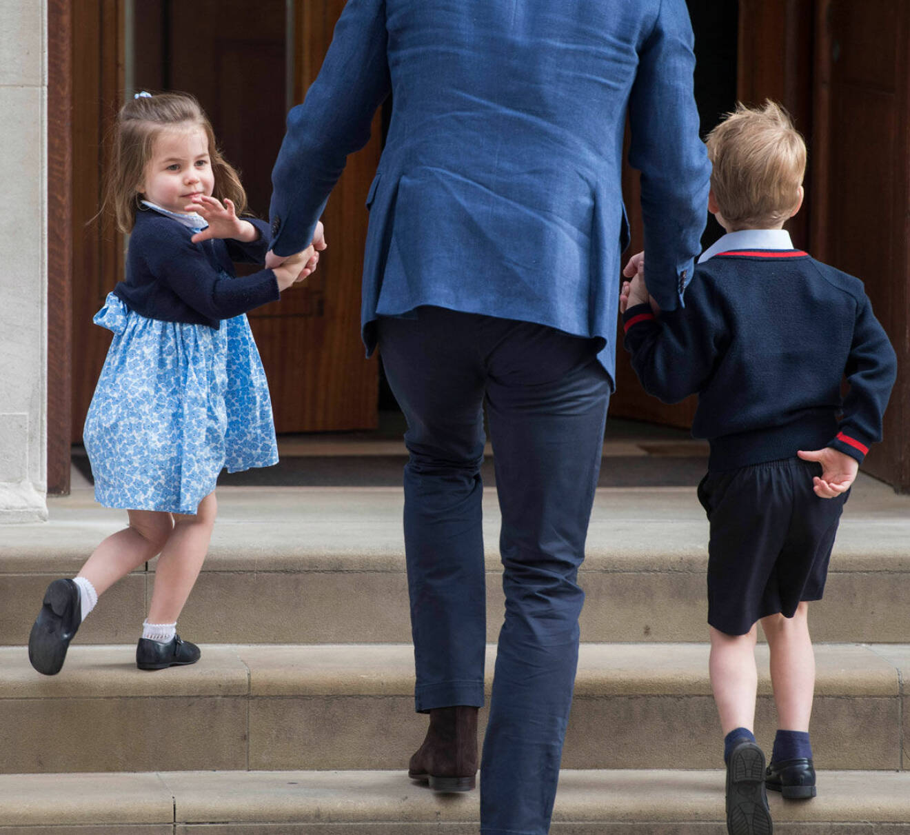 Prinsessan Charlotte vinkar och håller pappa William i handen. 