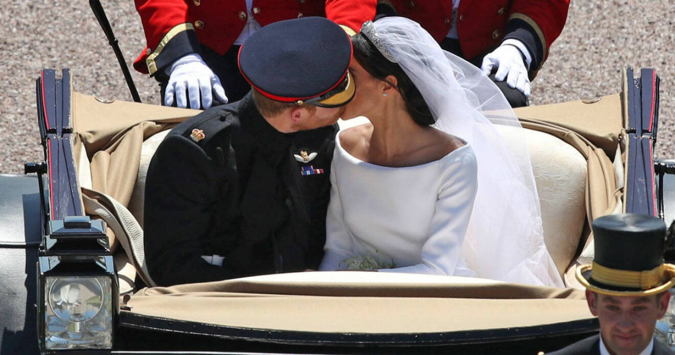 Prins Harry och Meghan Markle kysser i kortegen.