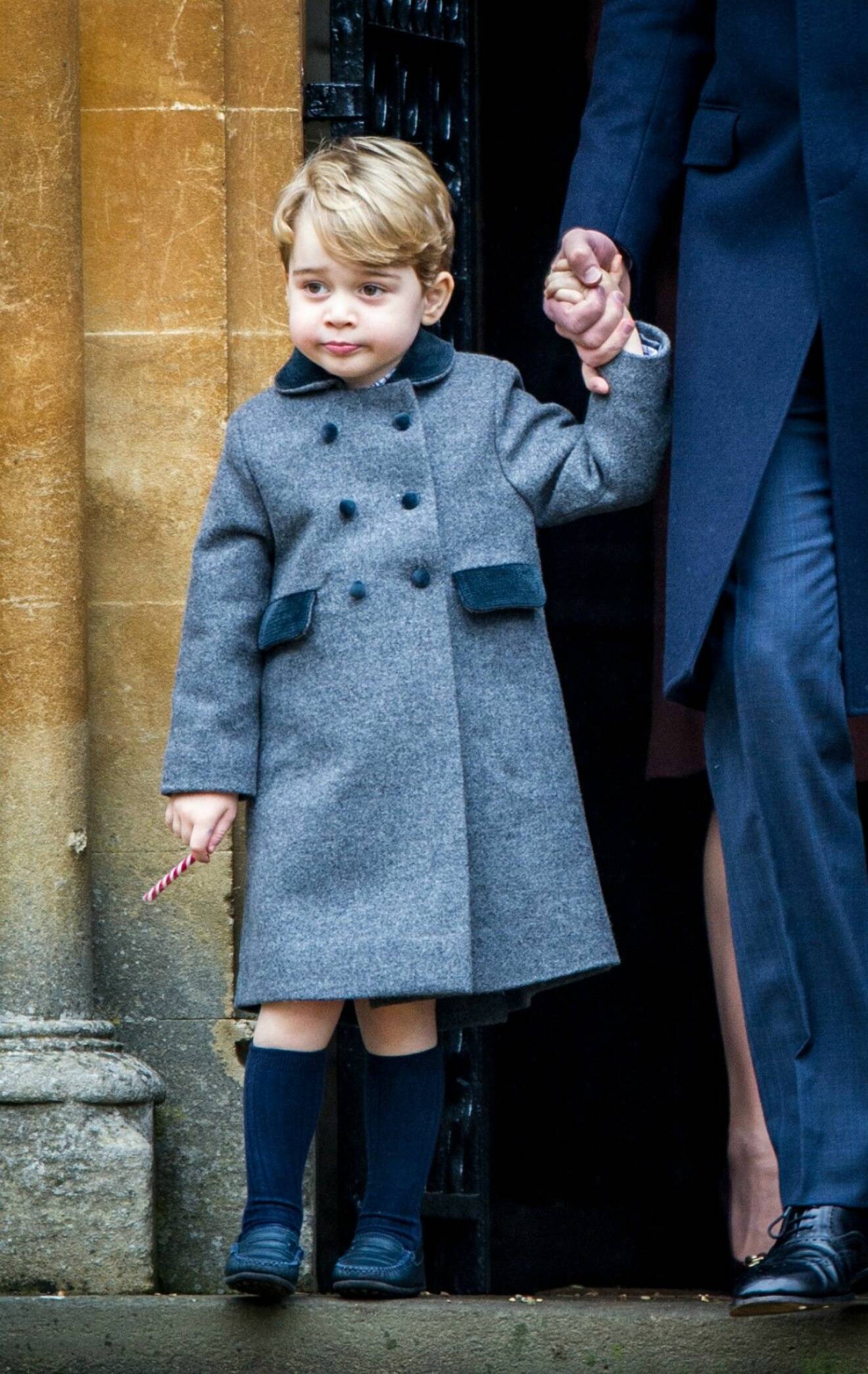 Prins George i kortbyxor mitt i vintern. Hans bara knän sticker fram under yllekappan.