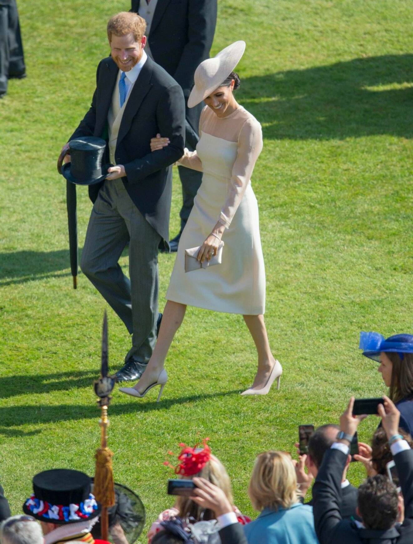 Meghan och prins Harry blir fotograferade av andra gäster under gardenpartyt på Buckingham Palace.