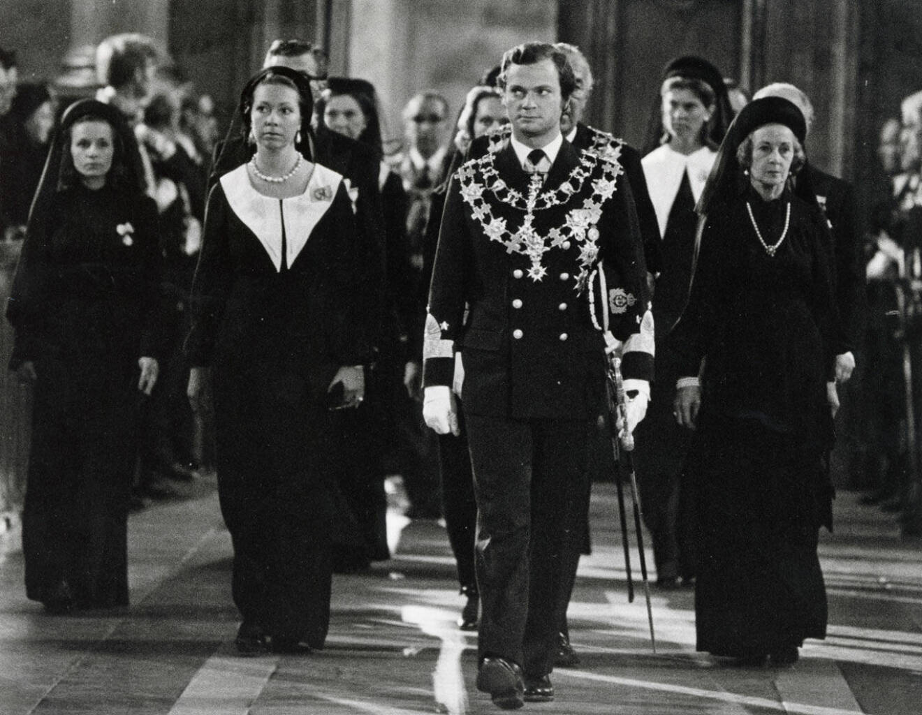 Kung Carl Gustaf med syster prinsessan Christina bakom sig på ena sidan och prinsessan Lilian på den andra. 