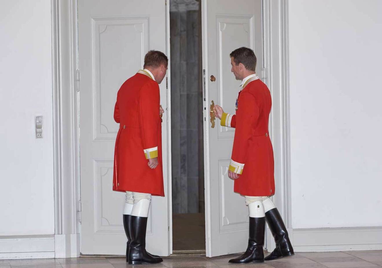 Två av drottning Margrethes hovlakejer öppnar dörrarna på Christiansborgs slott.