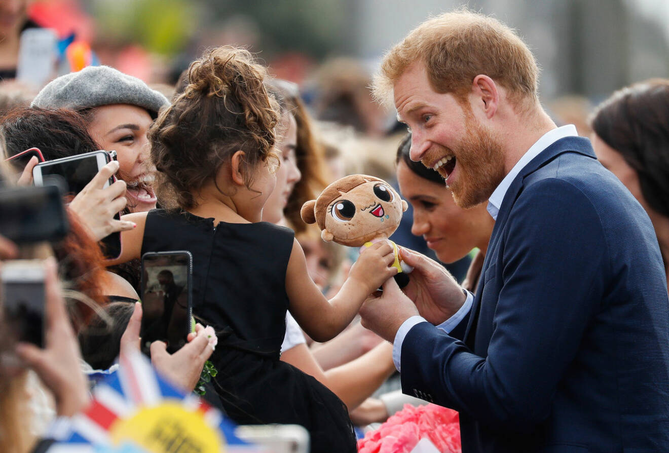 Prins Harry pratar med barnen som ger honom gosedjur.