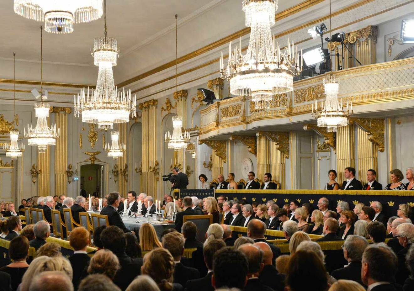 Svenska Akademien firar alltid sin högtidsdag runt den 20 december och ceremonin i Börssalen följer fortfarande Gustaf III:s anvisningar. I publiken sitter 400 särskilt inbjudna gäster och klädkoden är frack. Till höger ser du kungafamiljen.