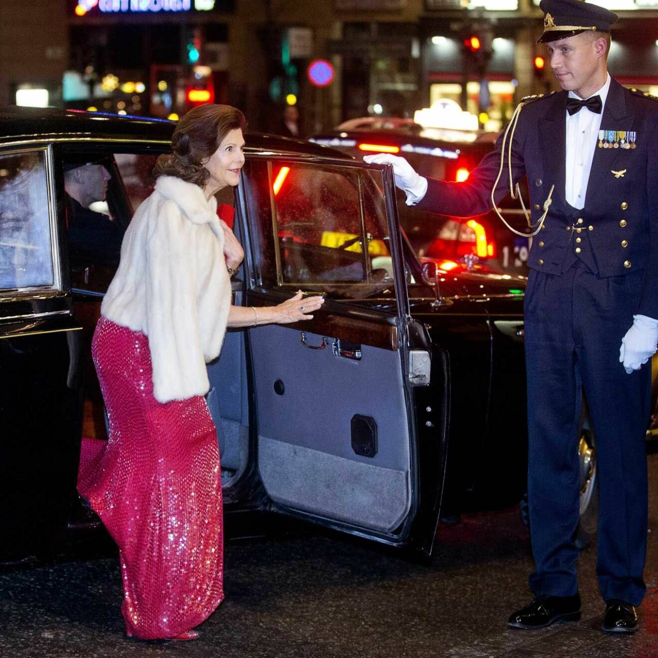 Drottning Silvia kliver ur limousinen vid sitt 70-årsfirande, klädd i en röd paljettklänning.