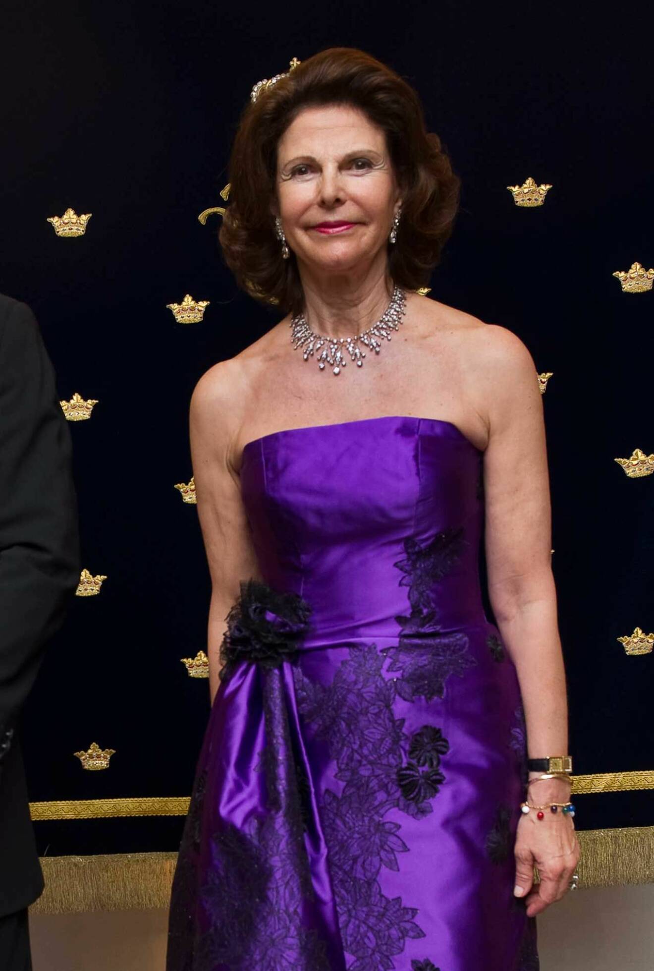 Drottning Silvia klädd i en axelbandslös aftonklänning i lila.