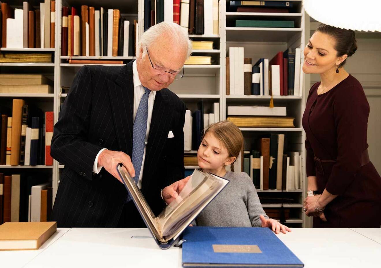 Kungen visar ett fotoalbum för prinsessan Estelle.