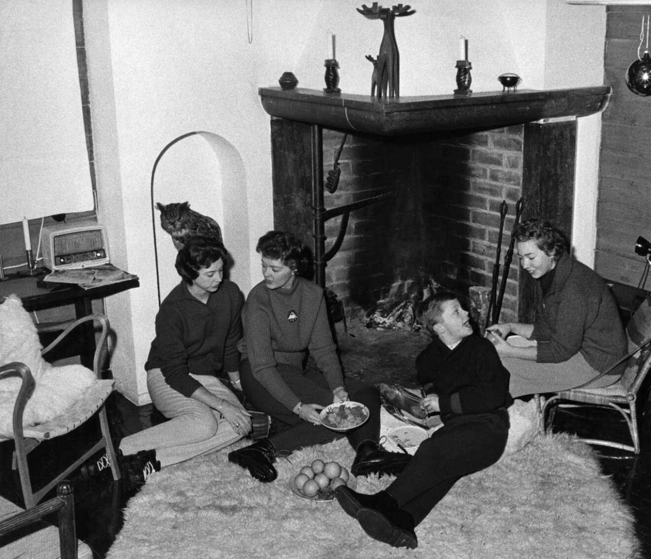 Kungen framför öppna spisen i stugan i Storlien 1959 med sina systrar Désirée, Birgitta och Christina.