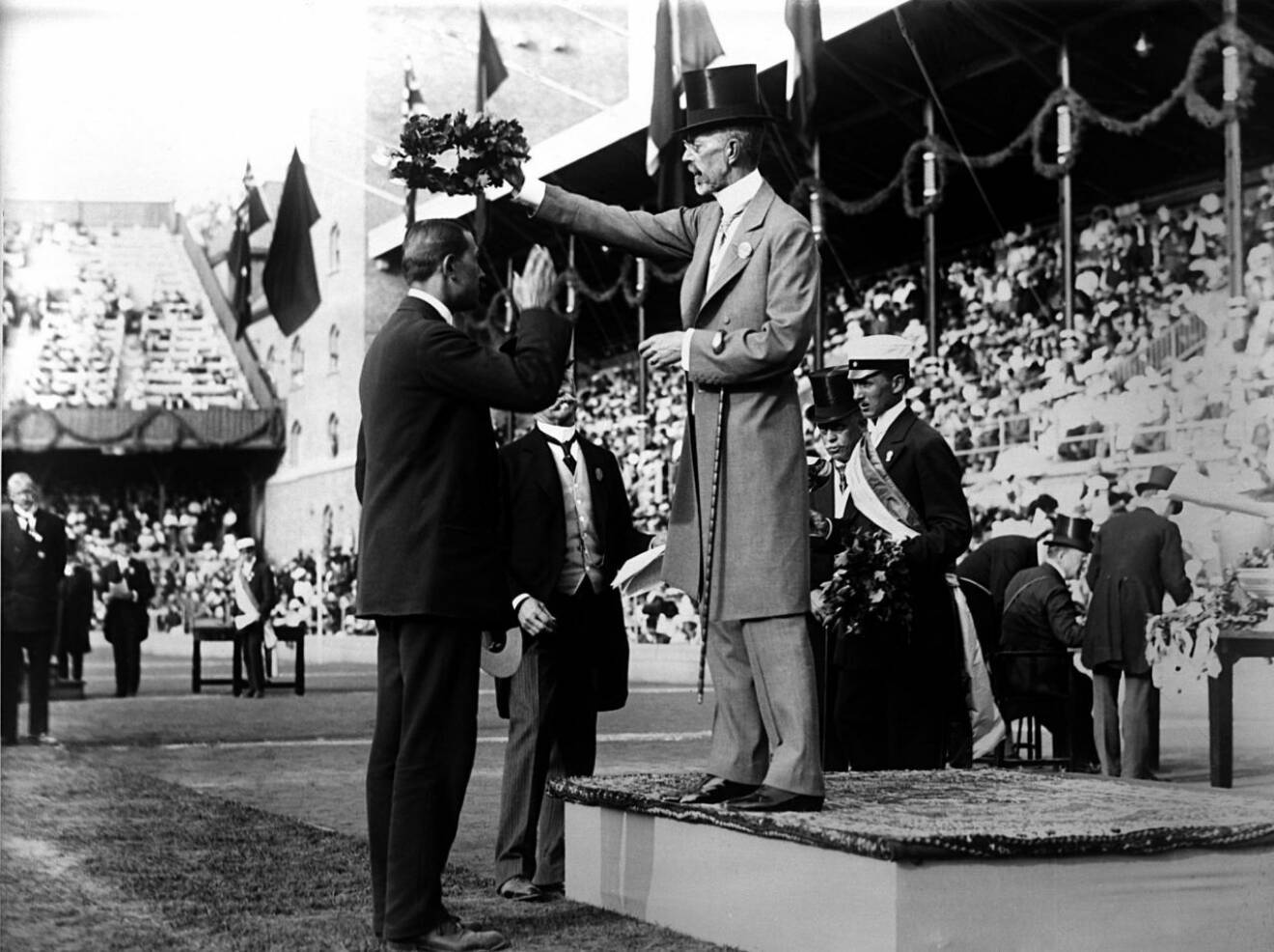 Ett foto från senaste gången OS hölls i Sverige 1912. Dåvarande kung Gustaf V ger en krans till vinnaren av spjutkastning. 
