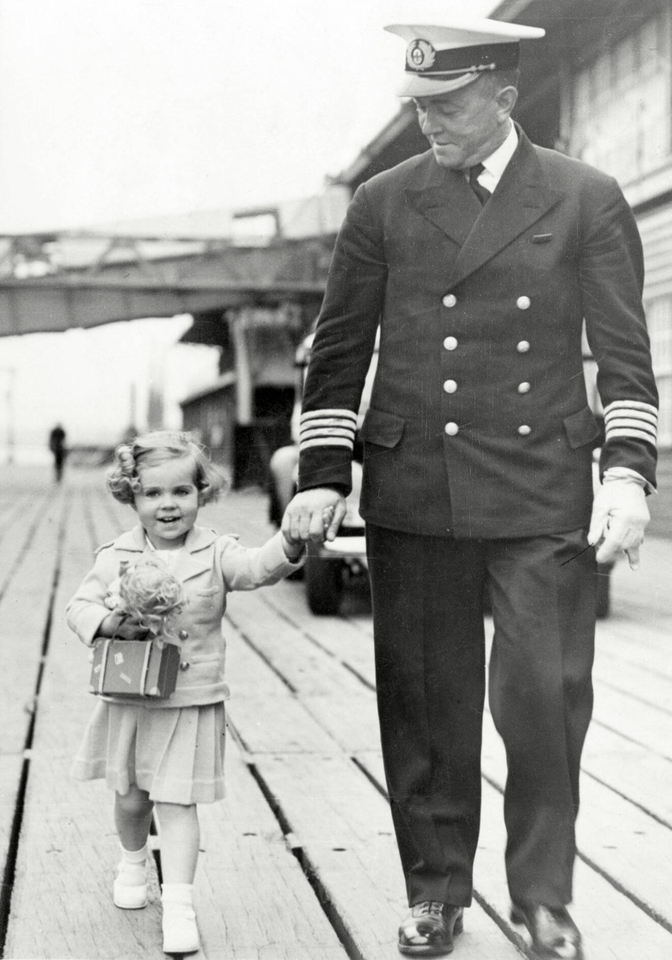Prinsessan Margaretha har anlänt till Tilbury, 1937, för att träffa sina föräldrar. Här går hon med kaptenen på fartyget Britannia som fört henne till England.