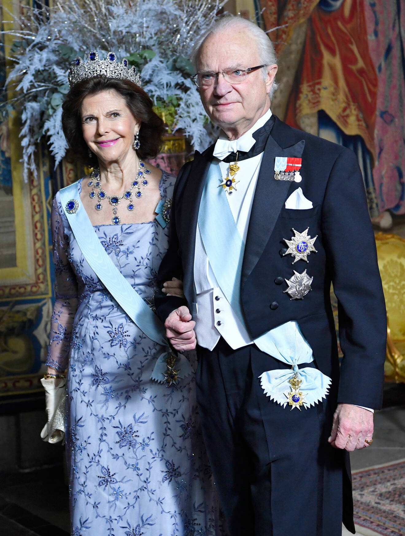 Drottning Silvia i blå aftonklänning och kung Carl Gustaf i frack.