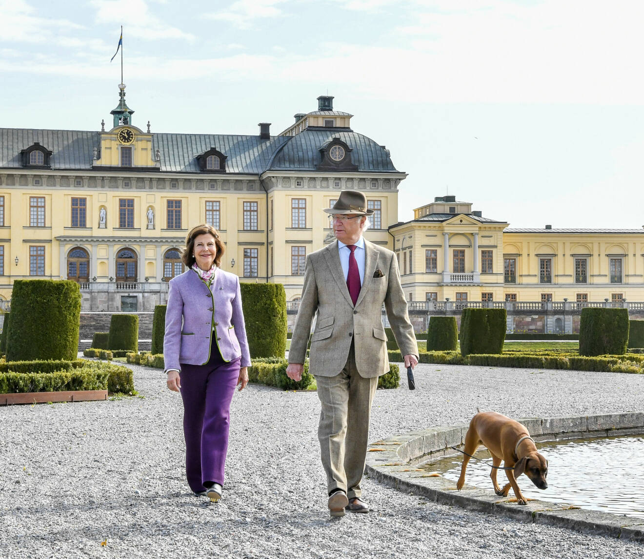 Kungaparet och hunden Brandie framför Drottningholms slott