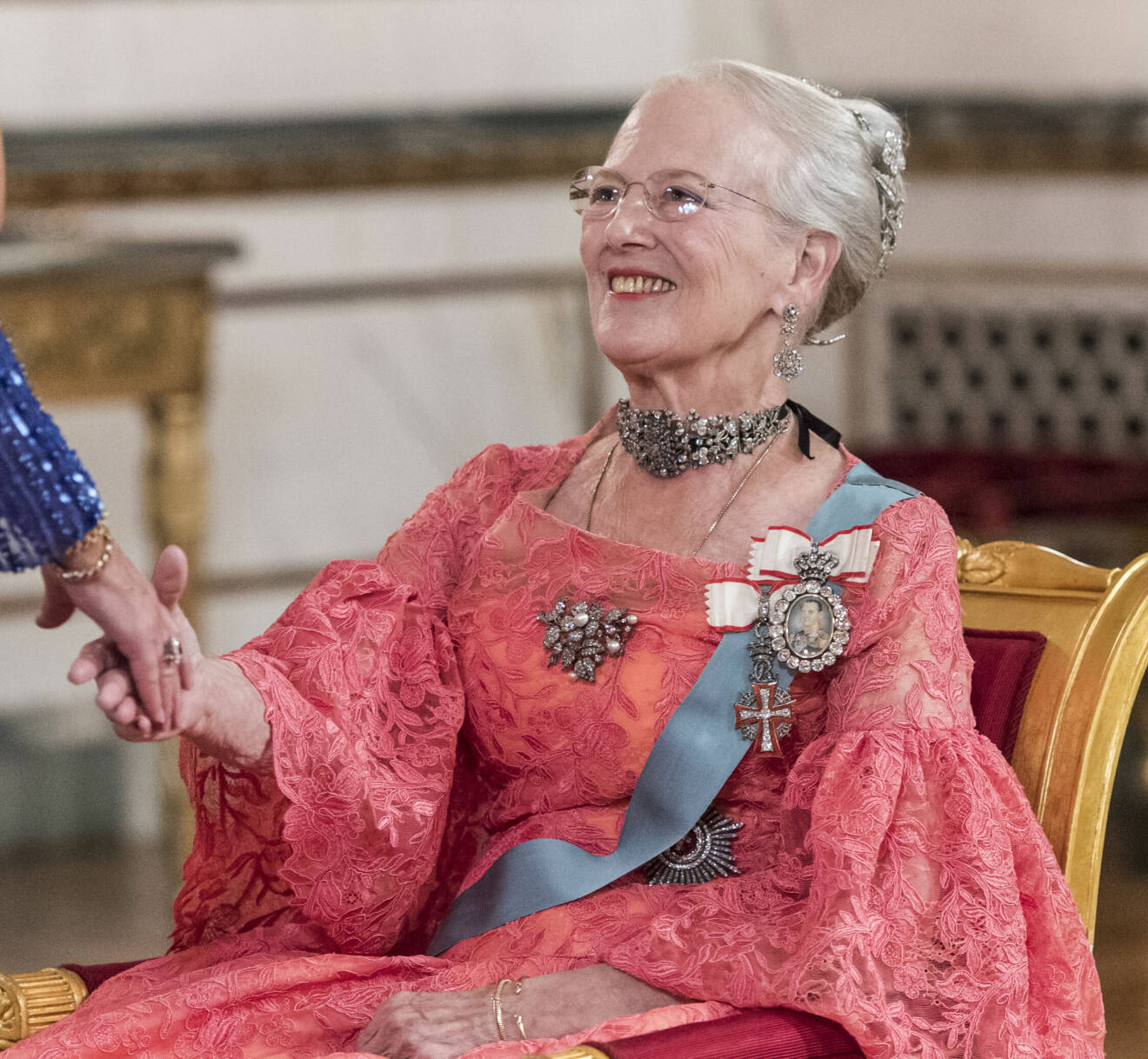 Drottning Margrethe hälsar sittande på en stol