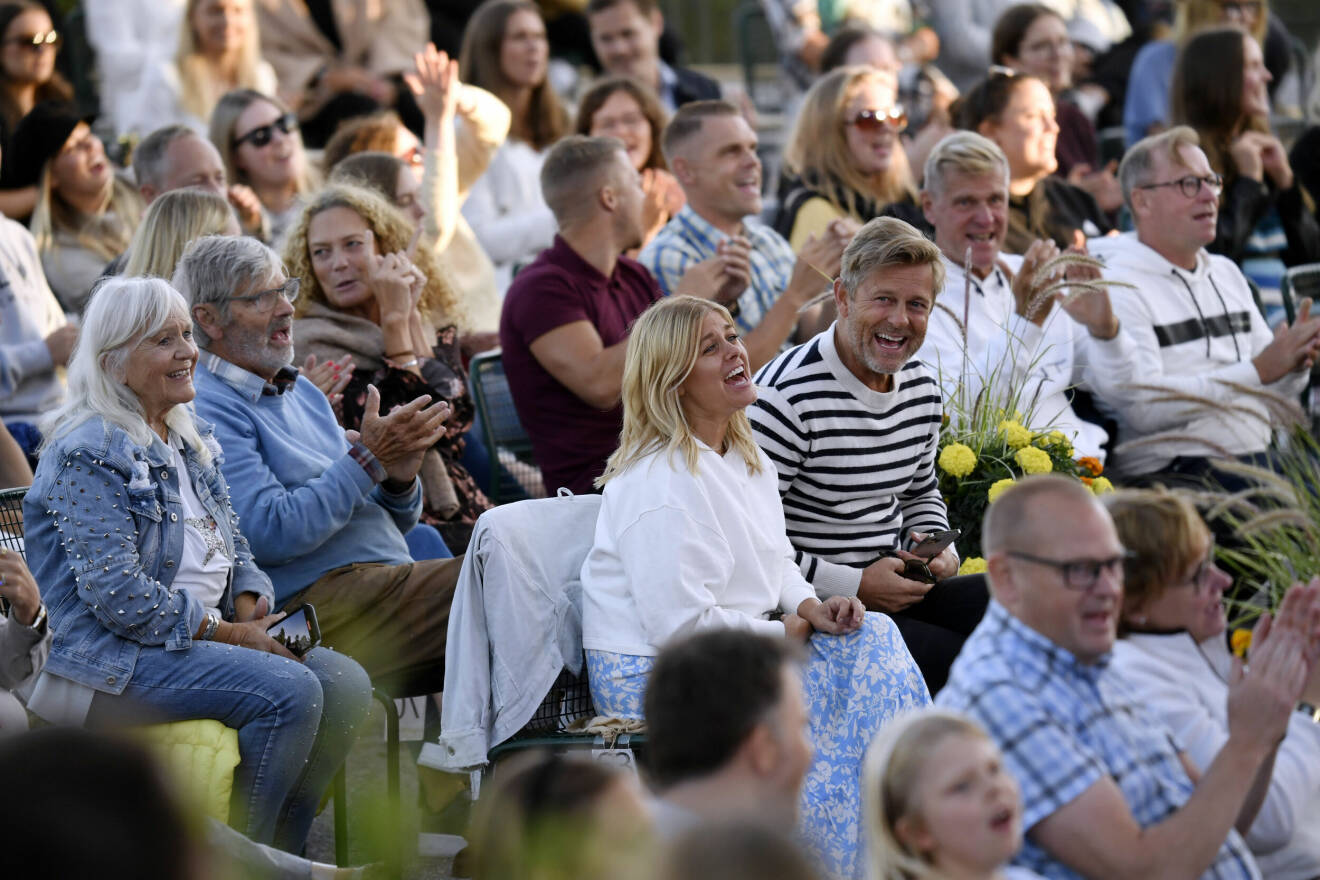 Pernilla Wahlgren skrattar i publiken till Allsång på skansen bredvid sin bror Niklas Wahlgren. Bakom henne sitter föräldrarna Christina Schollin och Hans Wahlgren