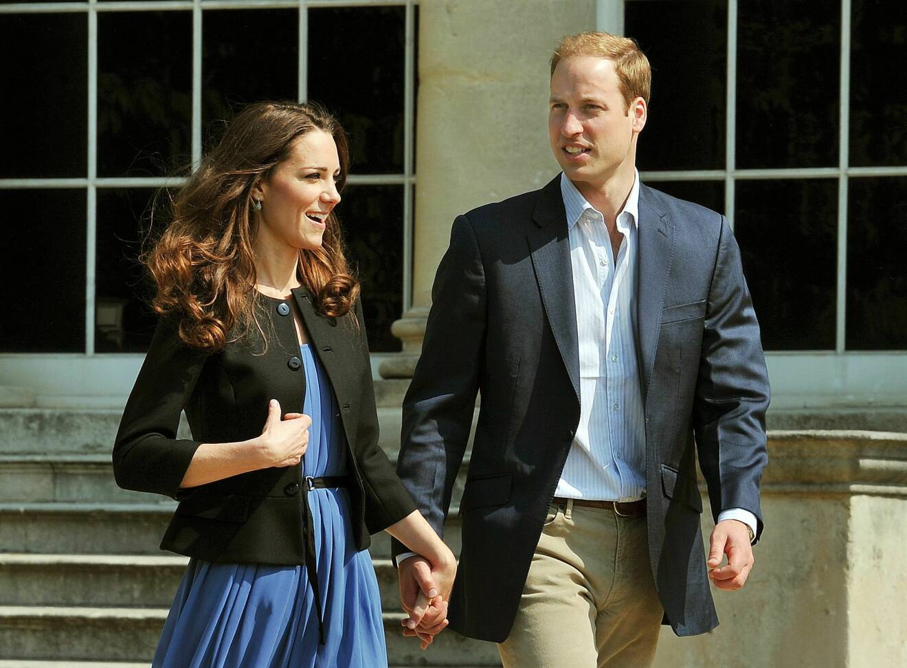 Prinsessan Kate och prins William håller handen och promenerar ut ur Buckingham Palace dagen efter deras bröllop.
