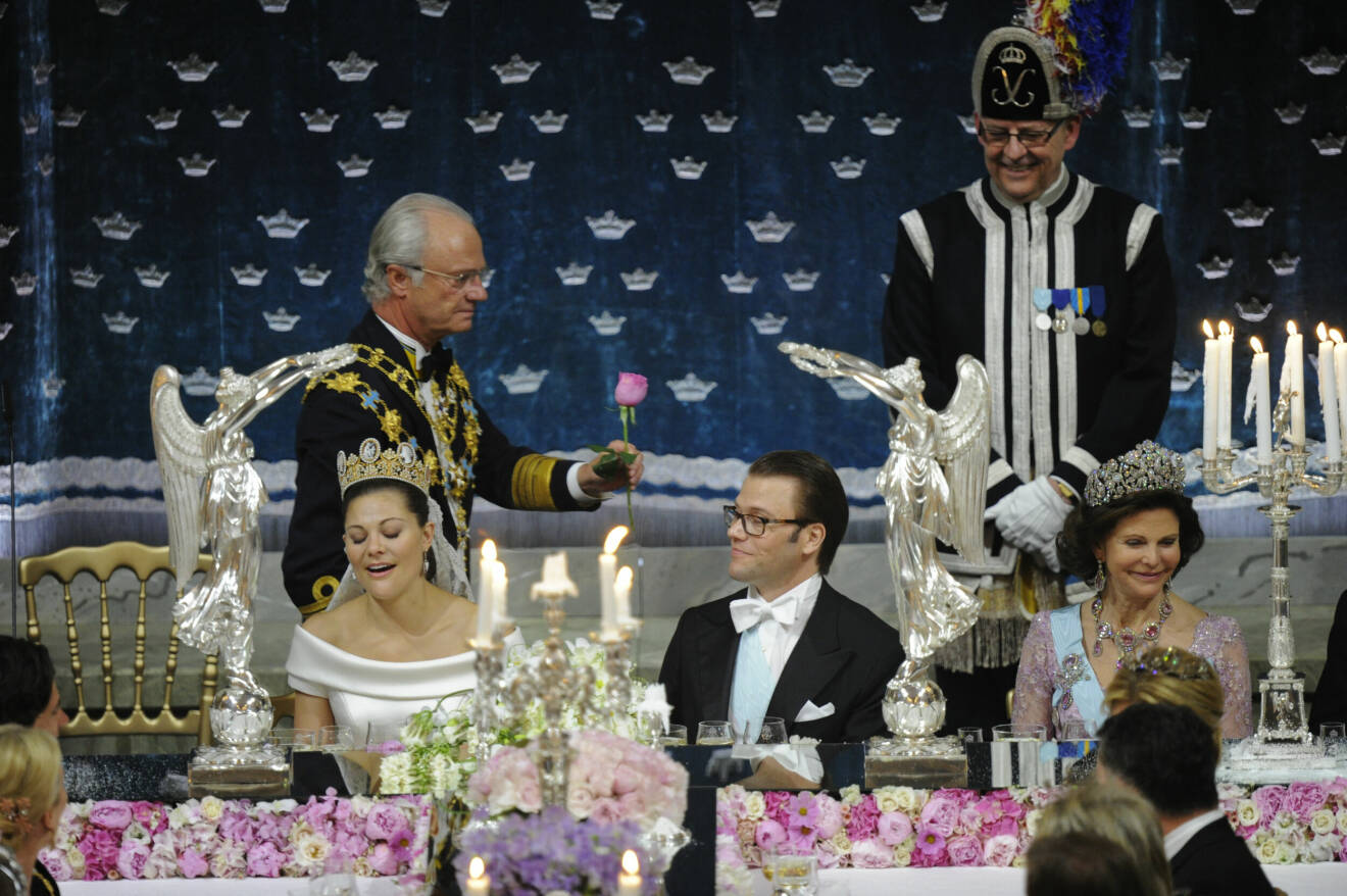 kung Carl XVI Gustaf överräcker en ros till drottning Silvia under bröllopsmiddagen för kronprinsessan Victoria och prins Daniel under bröllopsmiddagen i Rikssalen på Slottet i Stockholm efter vigseln på lördagen.