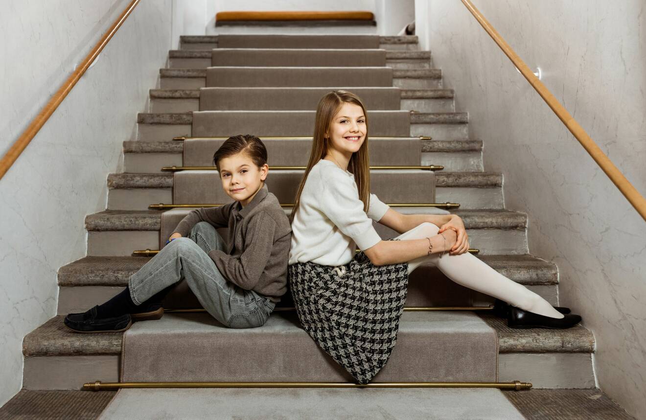 Prinsessan Estelle och prins Oscar sitter rygg mot rygg på en trappa i Haga Slott
