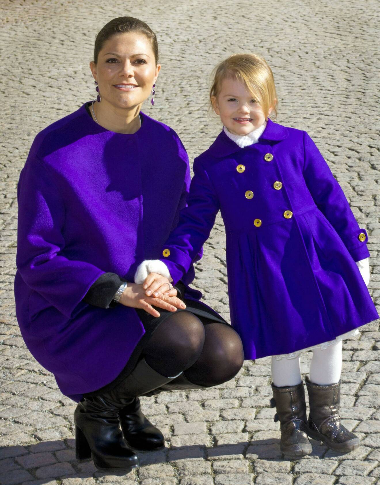 Prinsessan Estelle och kronprinsessan Victoria i lila kappor vid namnsdagsfirandet på slottet 2016