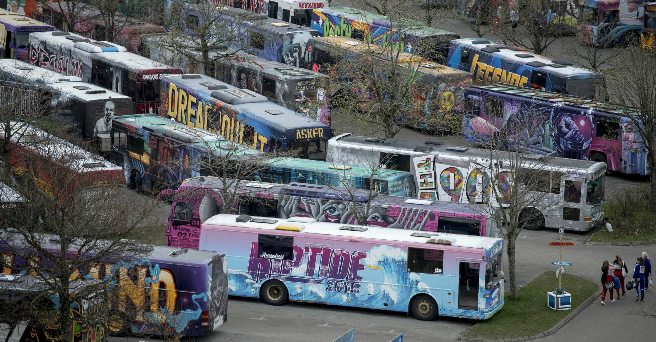 En parkering i Norge med flera målade bussar, så kallade russebussar
