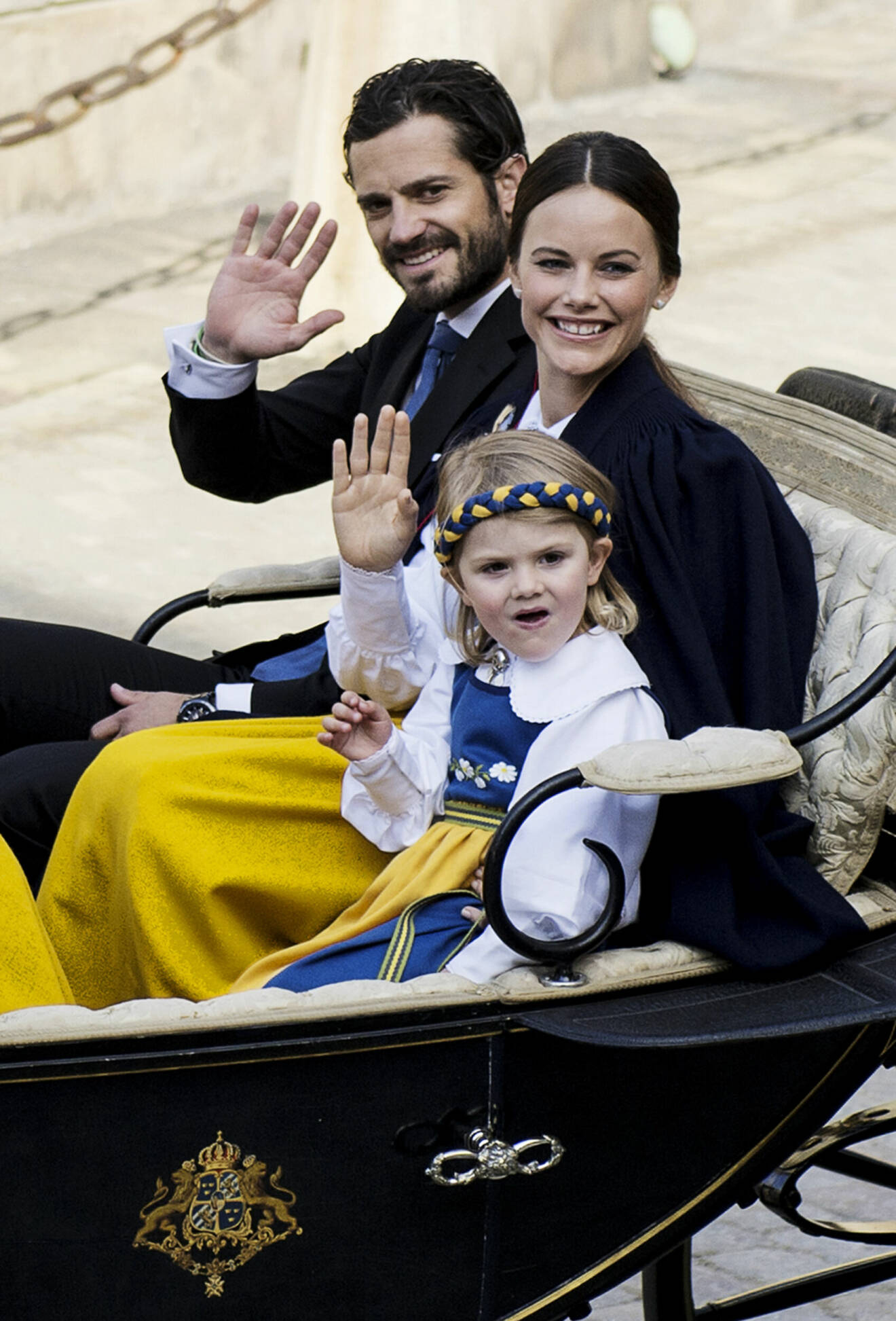 Prins Carl Philip och prinsessan Sofia åker vagn på nationaldagsfirandet med prinsessan Estelle som barn bredvid sig