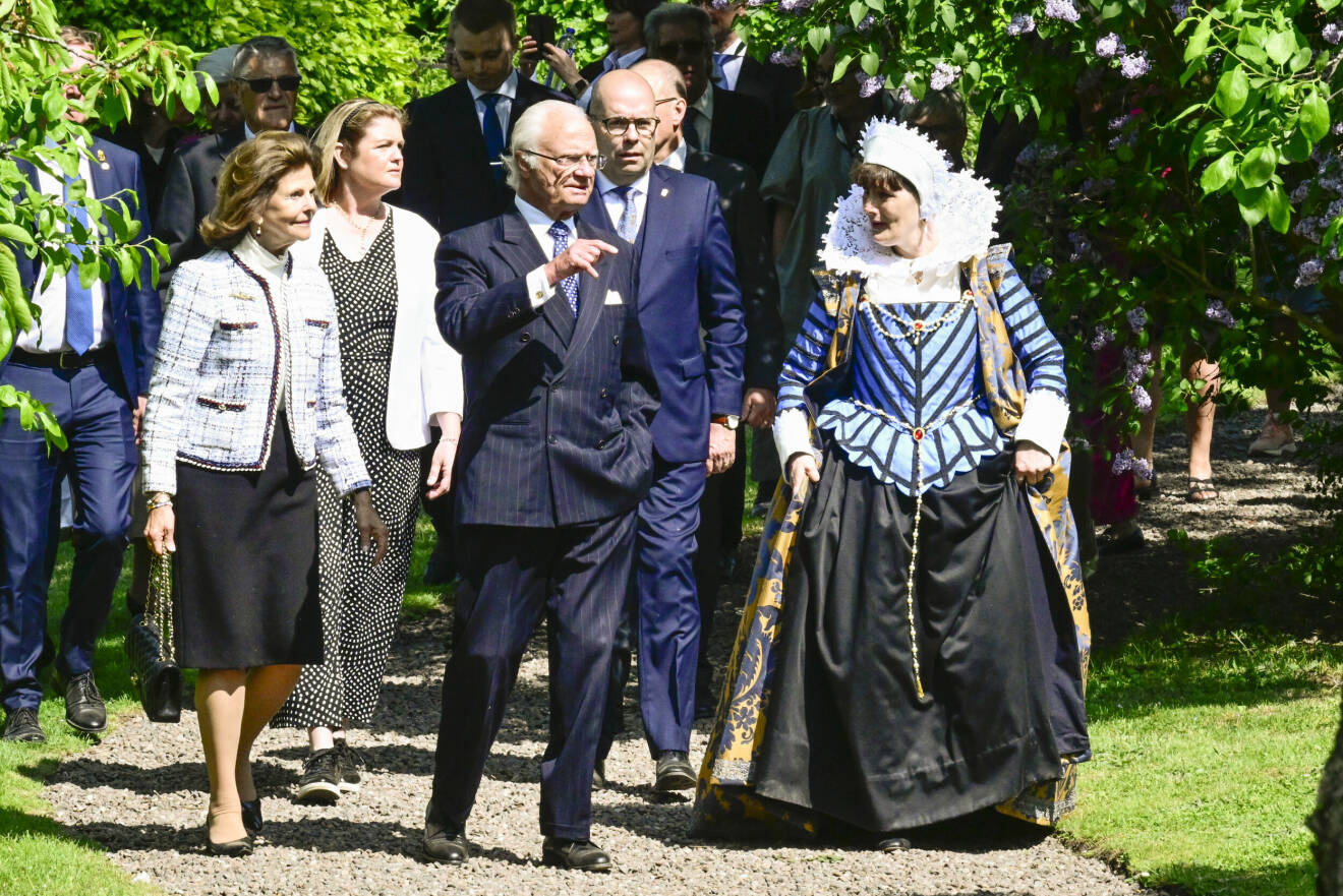 Kung Carl Gustaf och drottning Silvia under en historievandring i Linköpings slottsträdgård och möter längs med vägen guider i tidstypiska kläder, under kungaparets besök i Östergötlands län. Under året reser kungaparet till 21 län med anledning av kungens 50-årsjubileum på tronen.