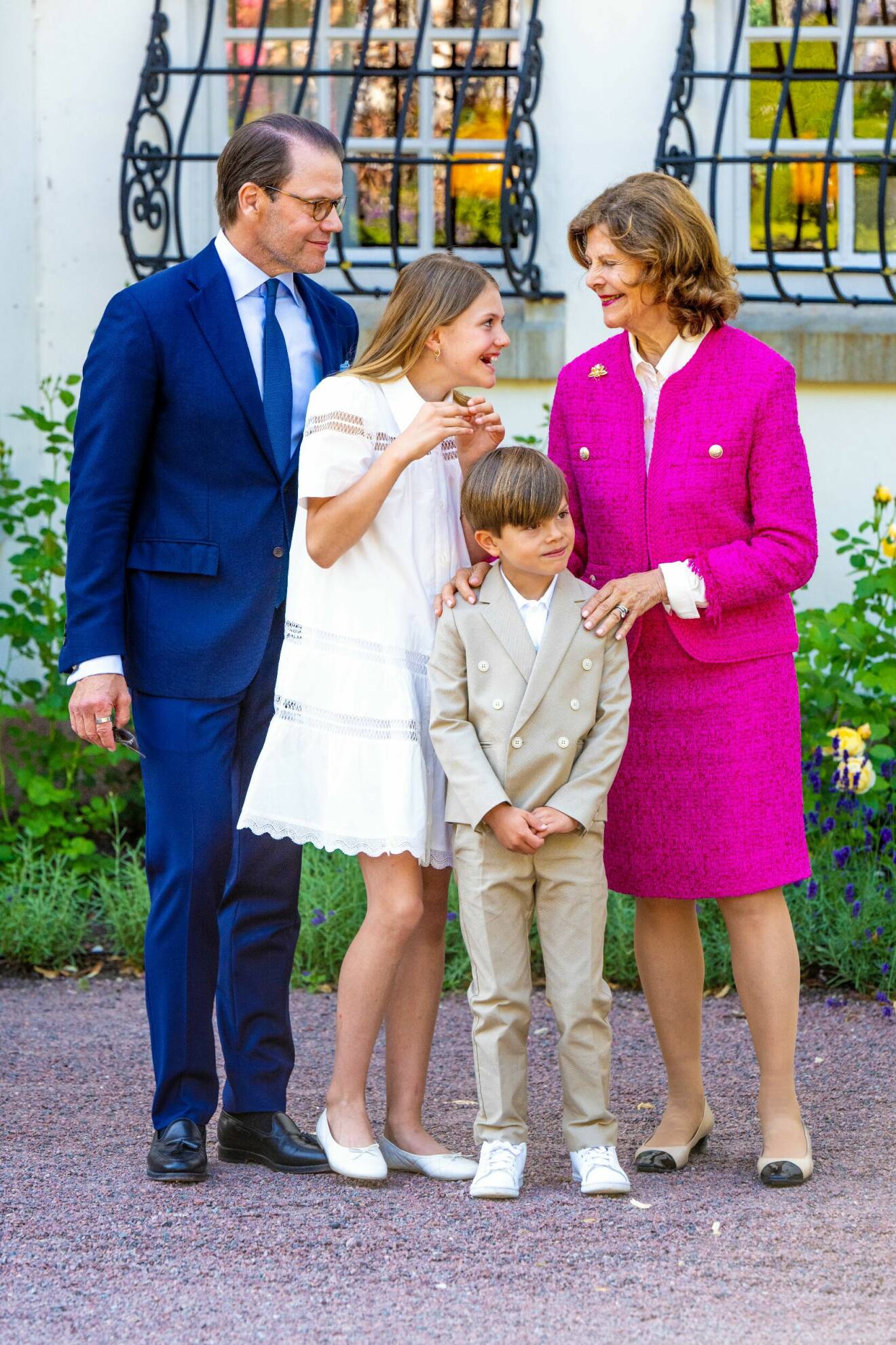 Prins Daniel tittar på när drottning Silvia och prinsessan Estelle skojar med varandra. Drottning Silvia håller händerna på prins Oscars axlar
