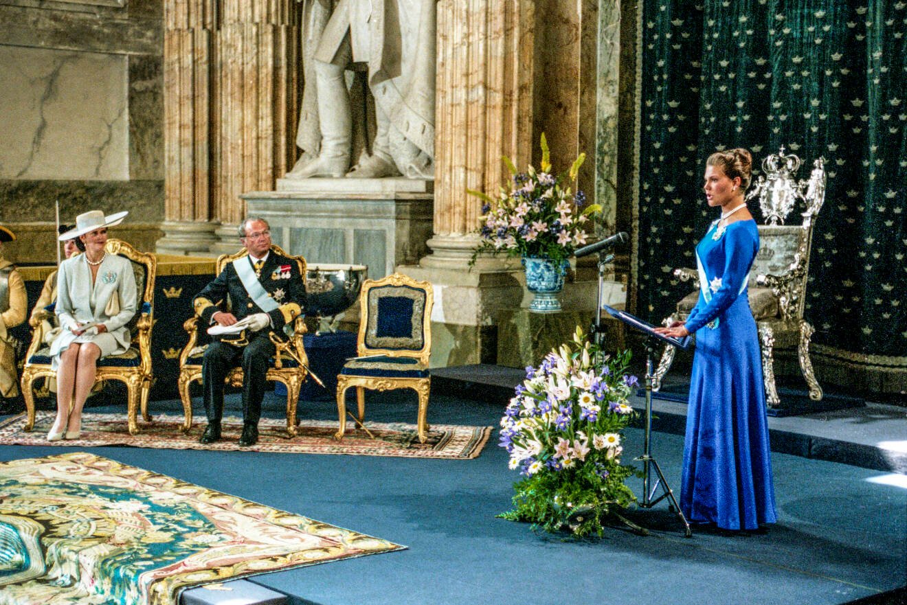 Kronprinsessan Victoria (t.h.) håller sitt första officiella tal till svenska folket framför drottning Silvia (t.v.) och kung Carl XVI Gustaf (mitten) i samband med myndighetsceremonin i rikssalen på Stockholms slott på 18-årsdagen.